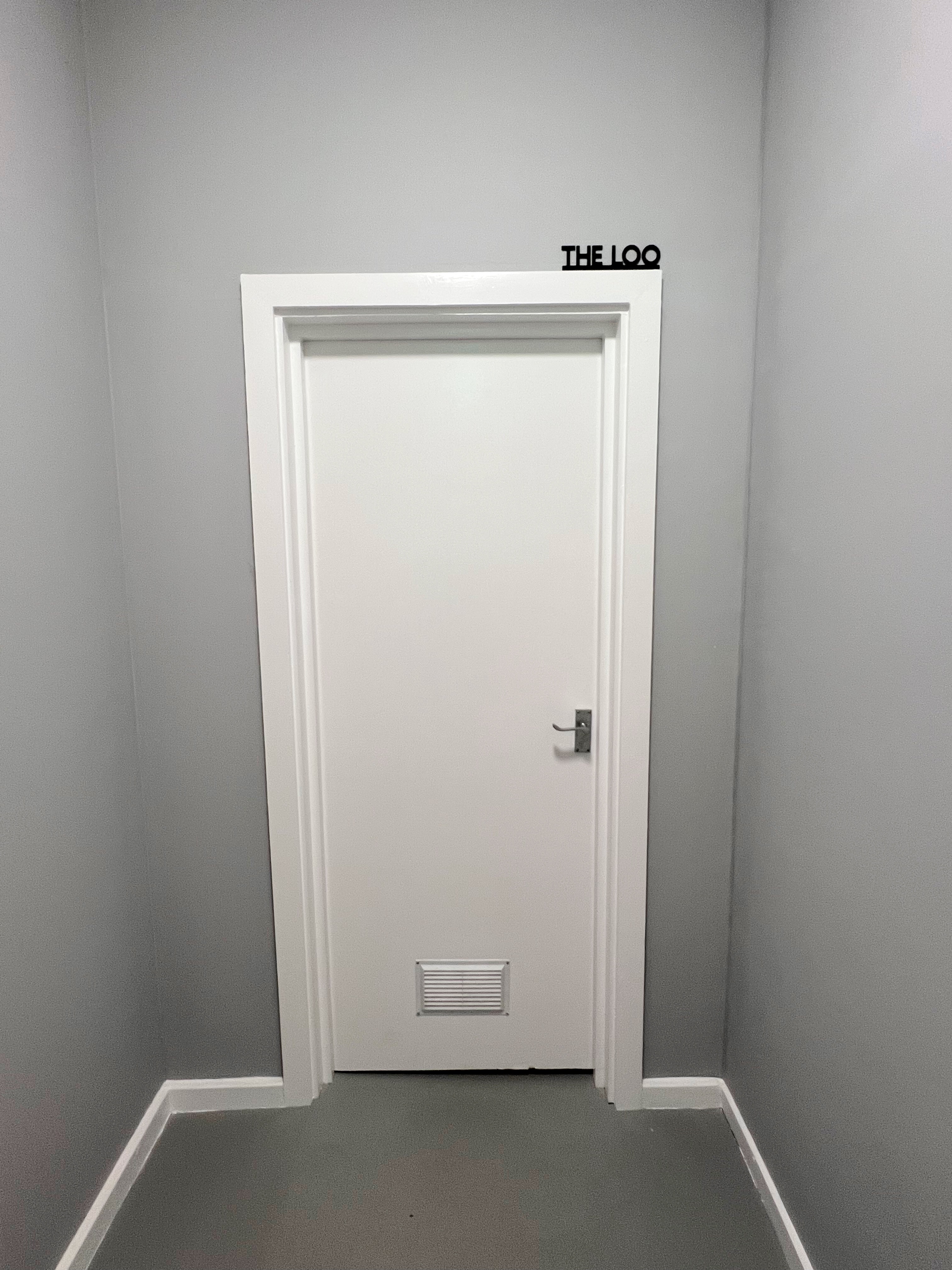 White door on gray wall in ARC STUDIOS, symbolizing accessible event space design.