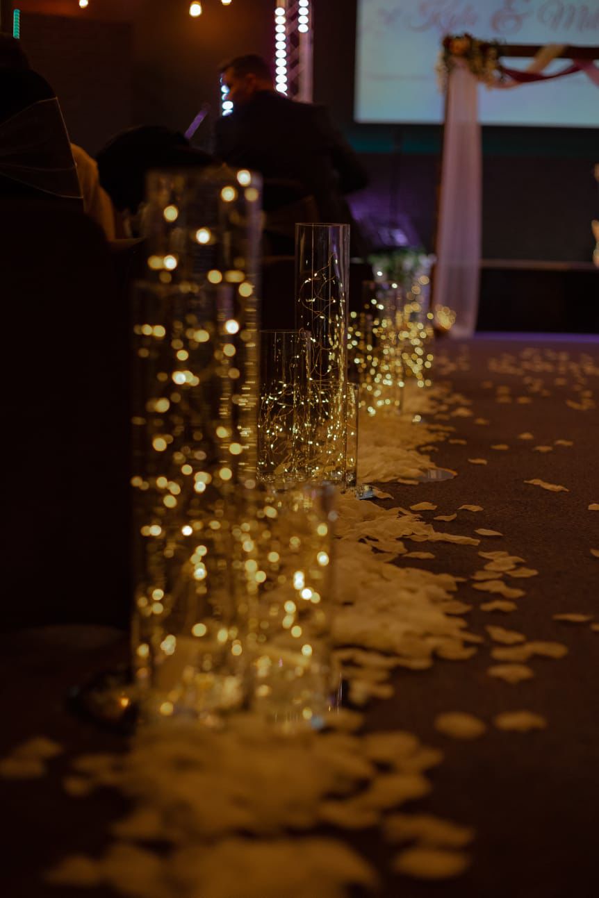 Elegant event hall in Victory Outreach Manchester with illuminated vases and romantic rose petals.
