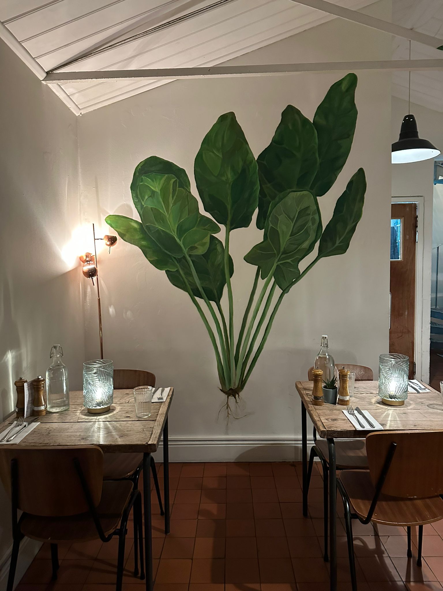 Cozy dining venue in Spinach East Dulwich with green leaf mural, ideal for events.
