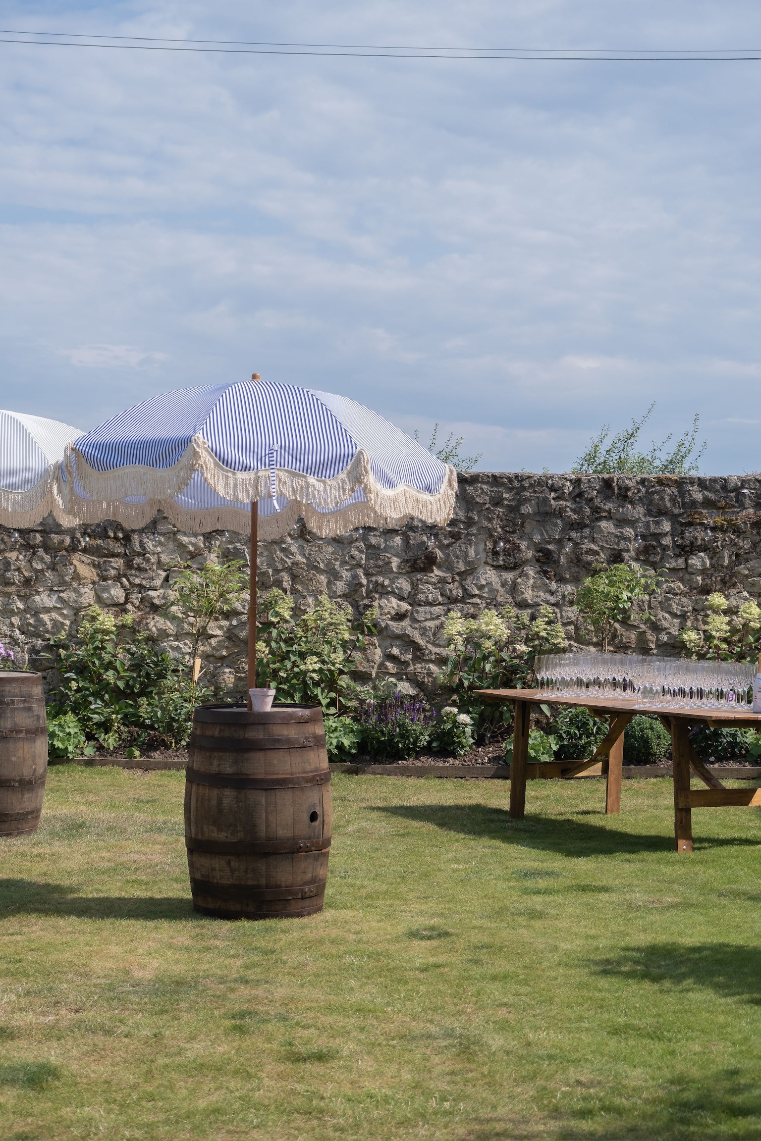 Charming outdoor event at Ruffynes Barn with striped umbrellas and rustic barrels.