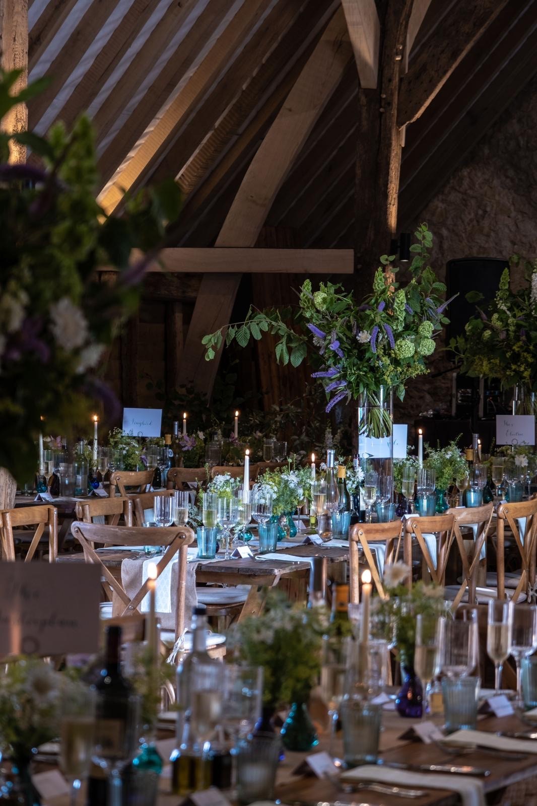 Elegant wooden tables with floral centerpieces in Ruffynes Barn for weddings and events.