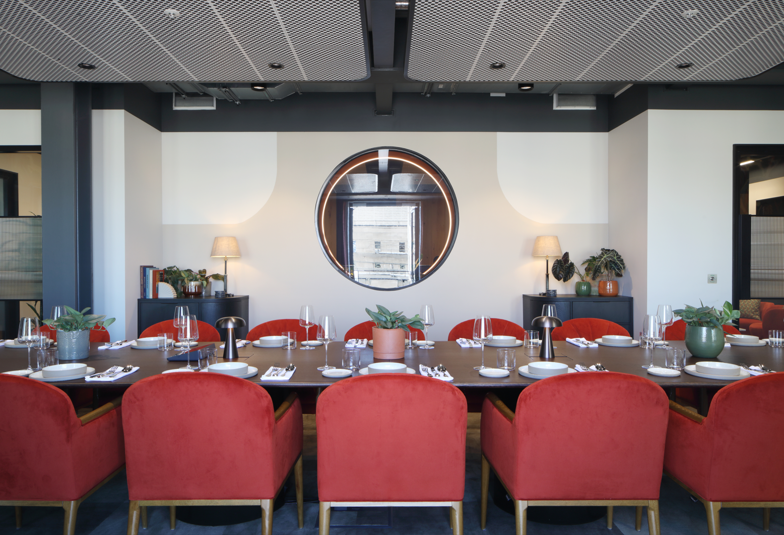 Stylish meeting space with round table and plush red chairs for intimate gatherings.