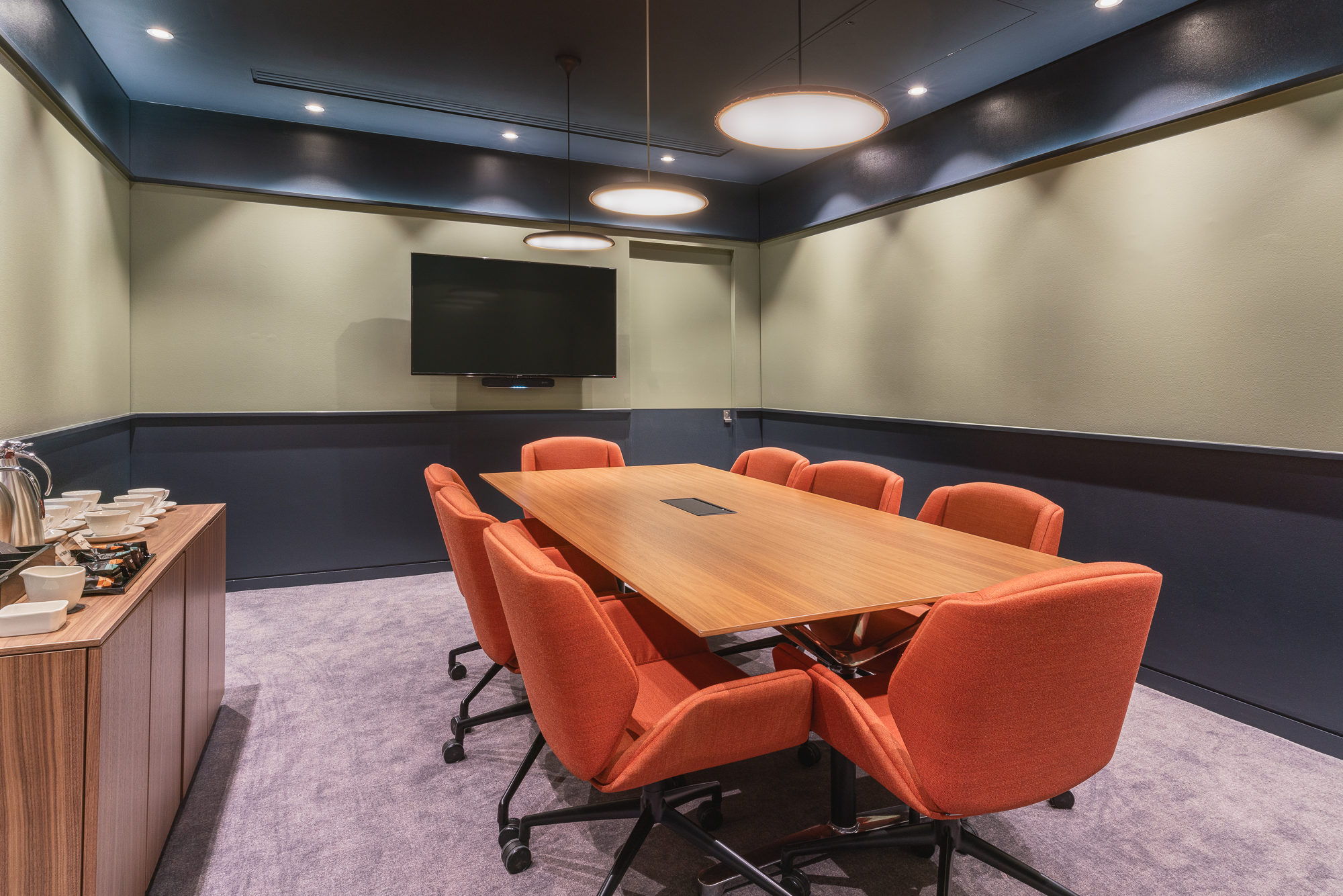 Modern conference room with wooden table and orange chairs for meetings and events.