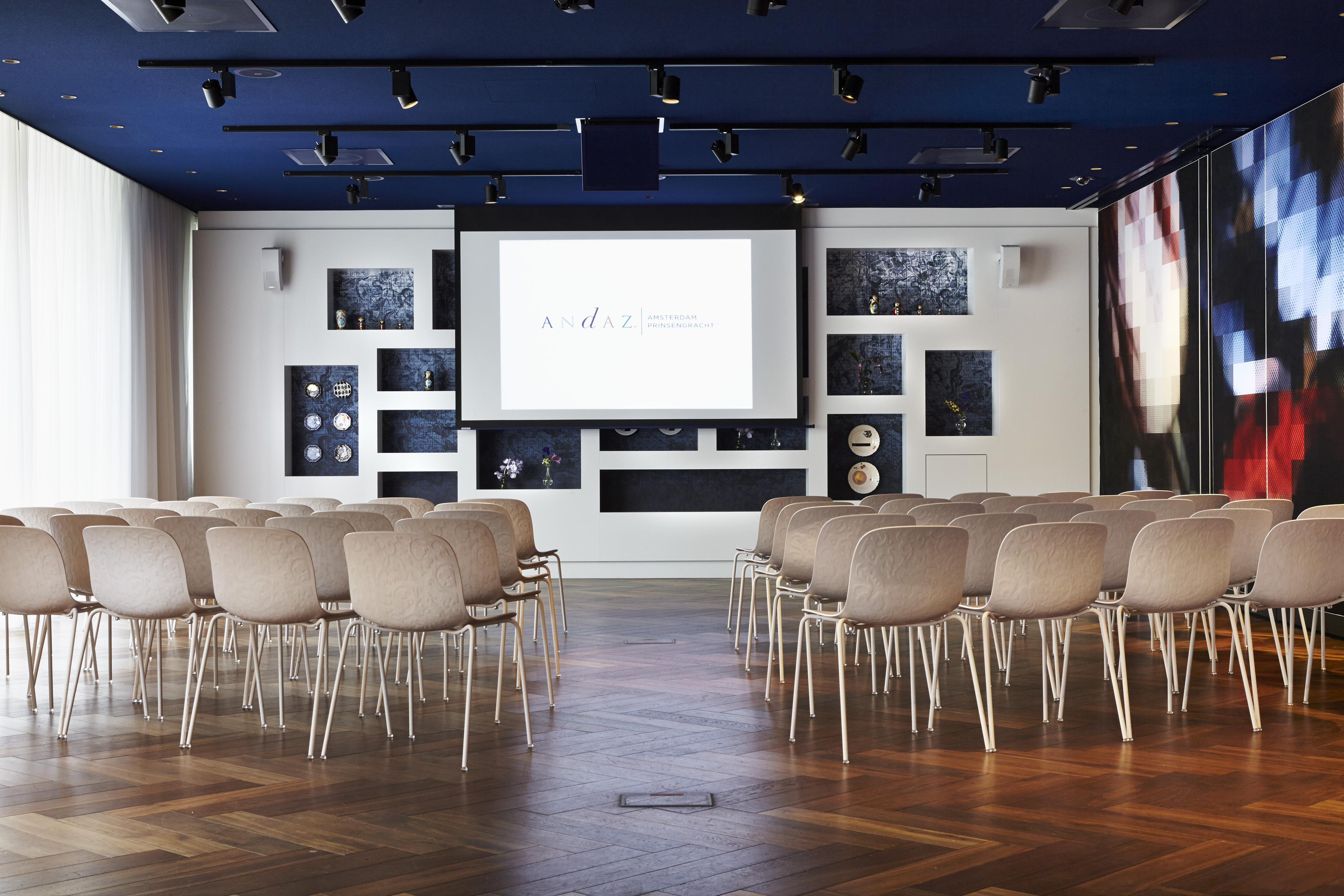 Modern meeting space in Andaz Amsterdam with large screen for corporate events.