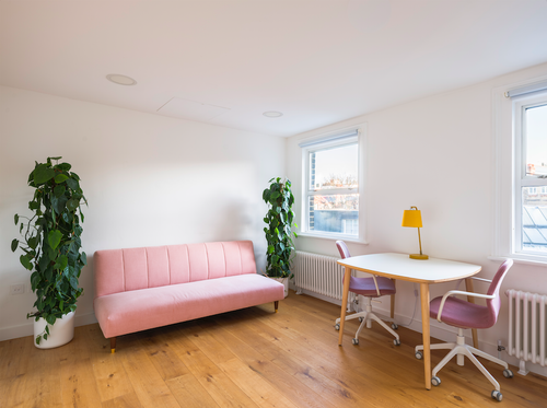 Bright minimalist meeting room with pink sofa, ideal for brainstorming sessions.