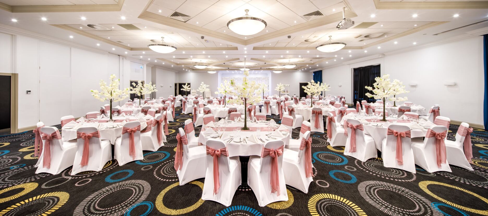 Telford Suite at Mercure Hotel, elegant wedding venue with round tables and floral decor.