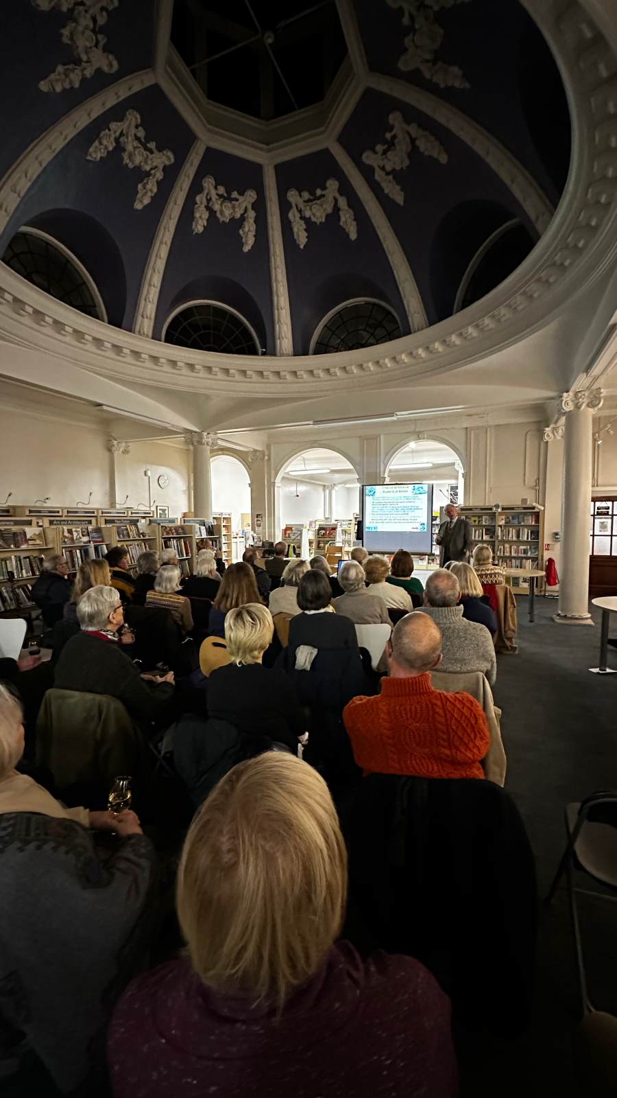 West Greenwich Library seminar with engaged audience in a cozy, book-filled setting.