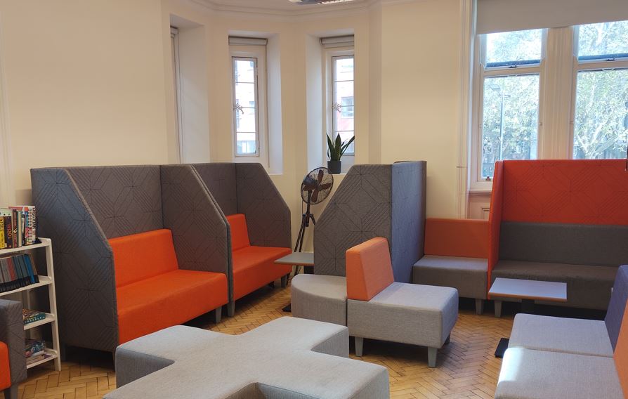 Modern Collaboration Hub in BSC London with vibrant gray and orange seating for meetings.