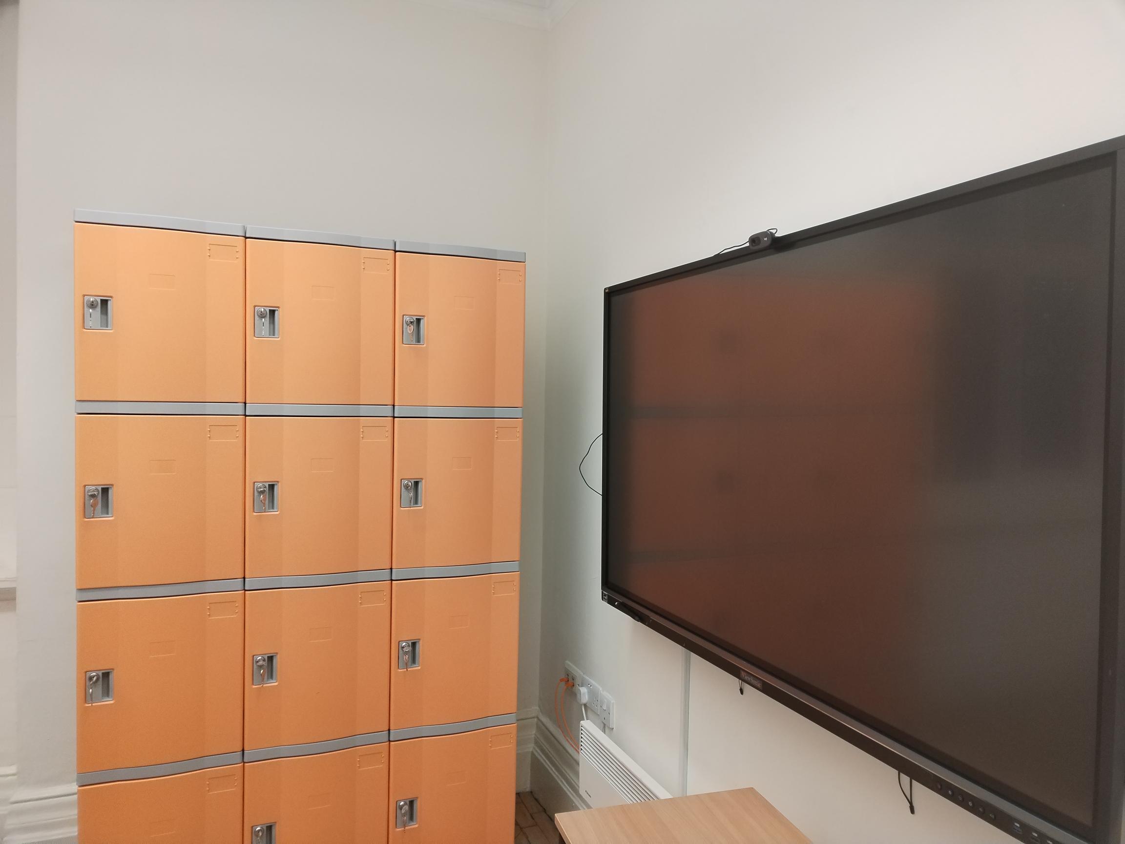 Collaboration Hub in BSC London with orange lockers, ideal for meetings and events.