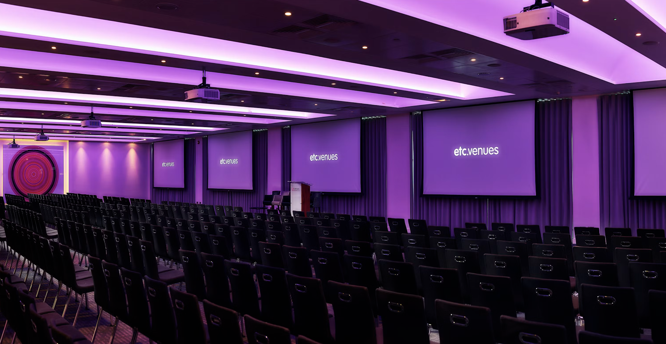 Modern conference room with black chairs and screens, ideal for events and networking.