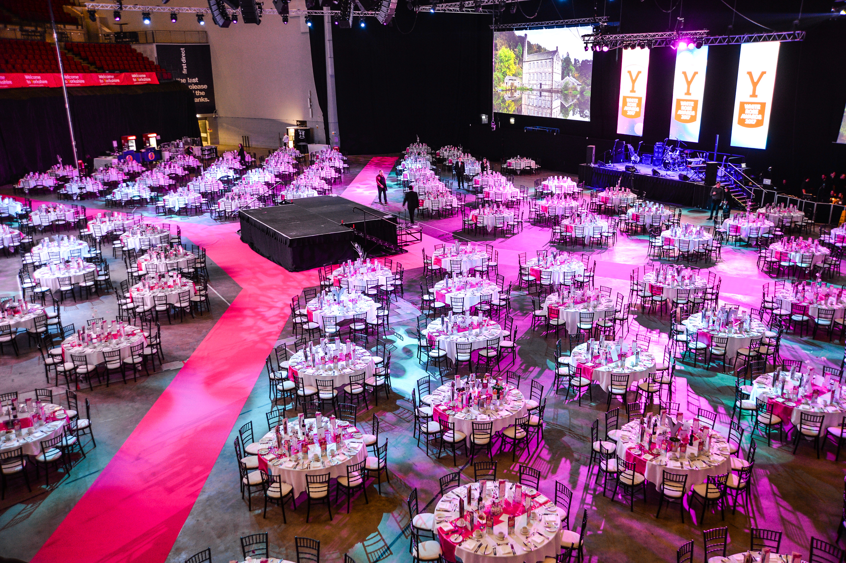 Formal event space in First Direct Arena Leeds with round tables and pink accents.