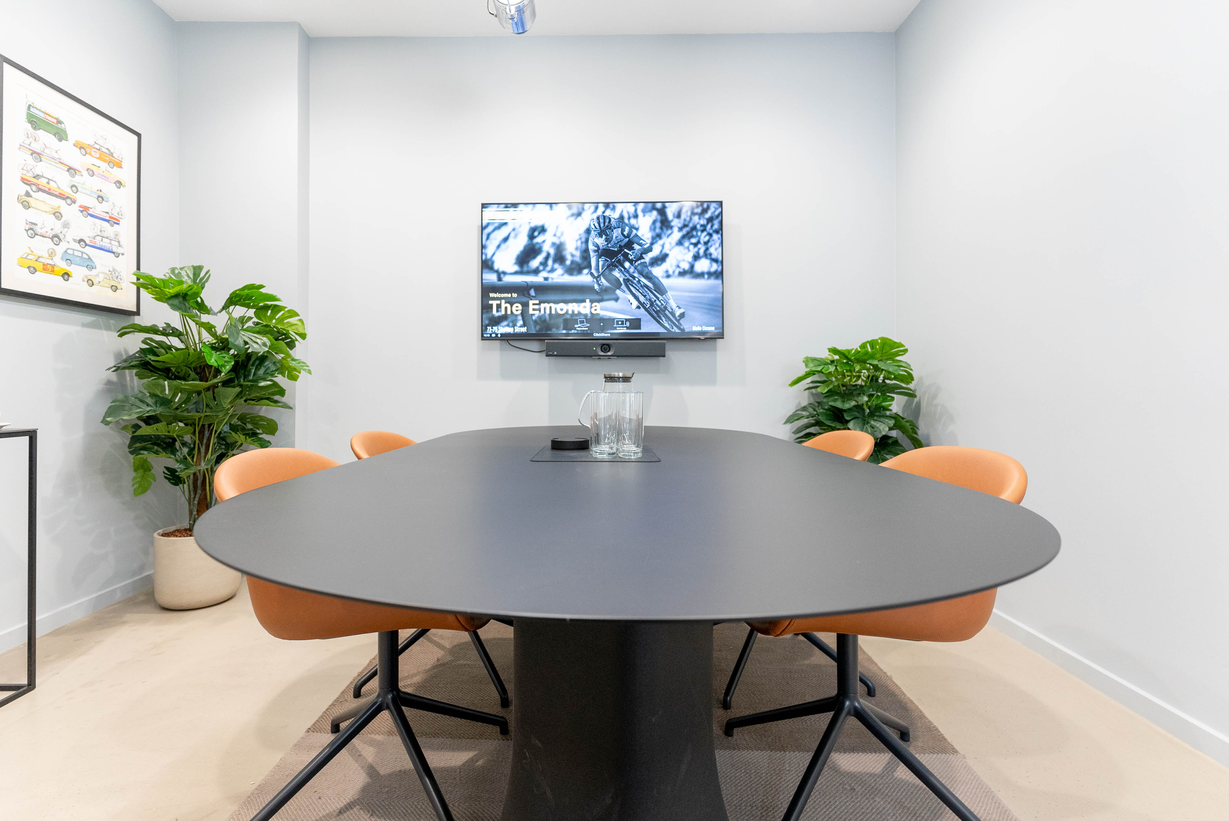 Modern meeting room with oval table, large screen, and greenery for collaborative events.