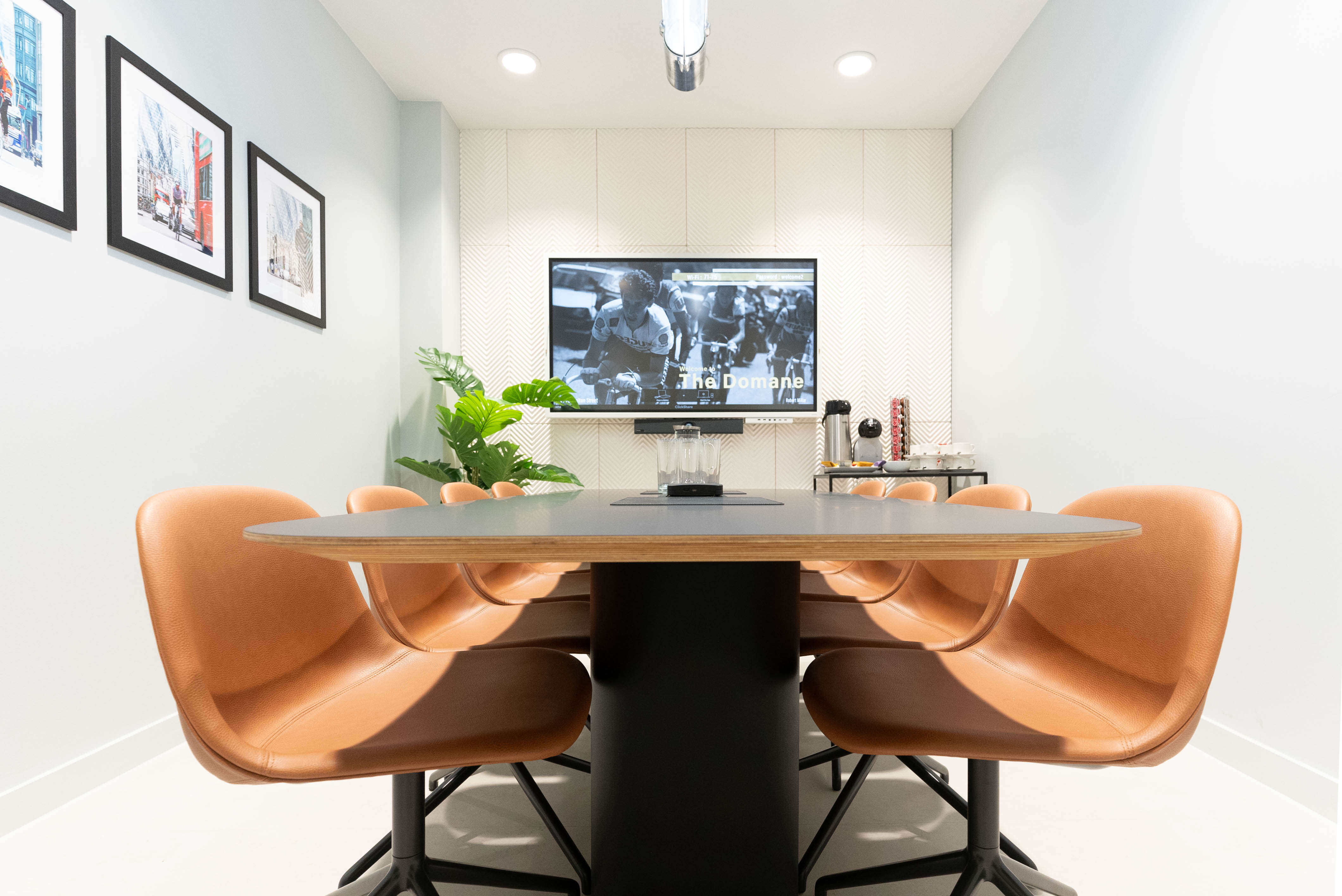 Modern meeting room in The Domane, featuring a sleek table and wall-mounted screen.