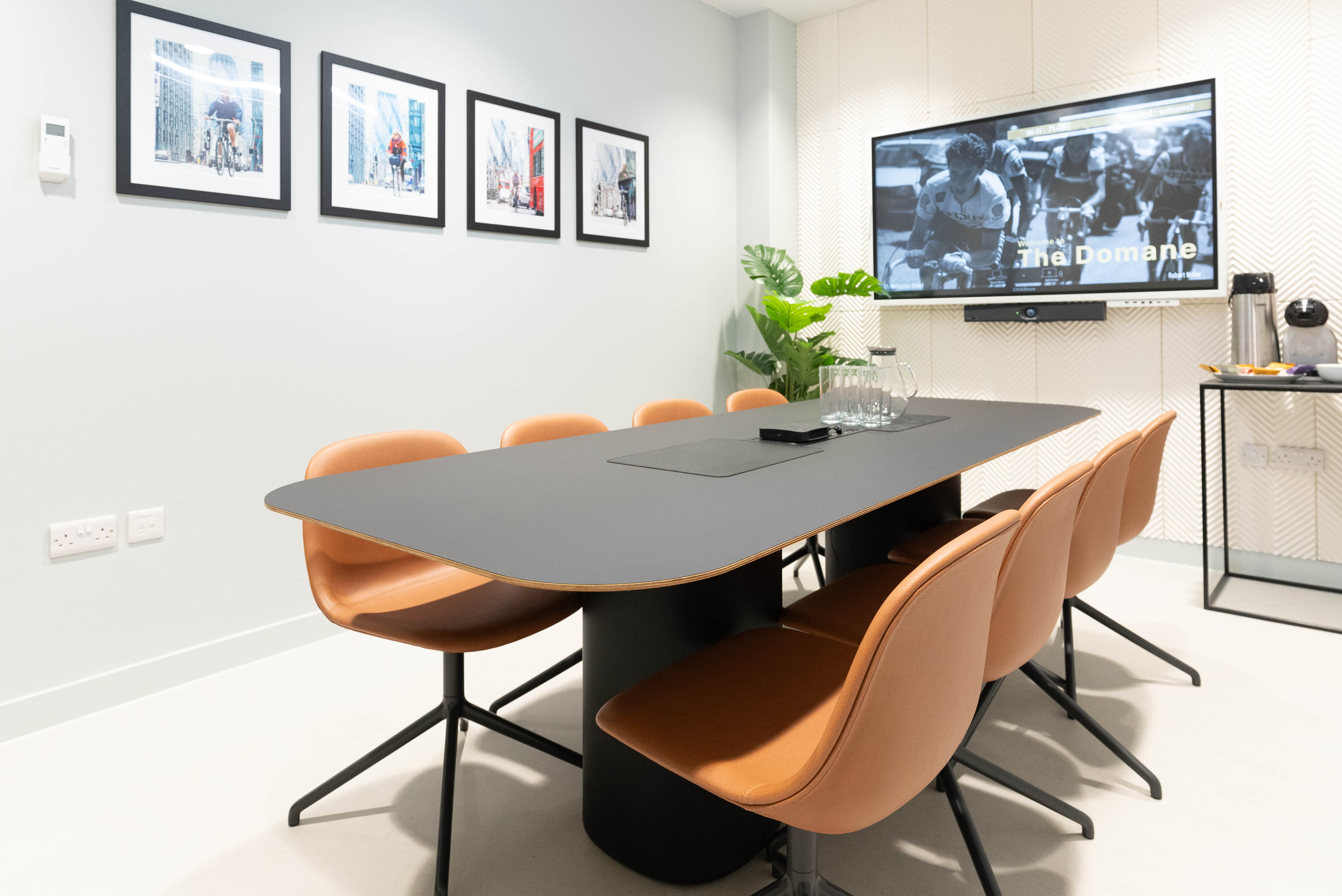 Modern meeting room with black table, orange chairs, ideal for collaboration and presentations.