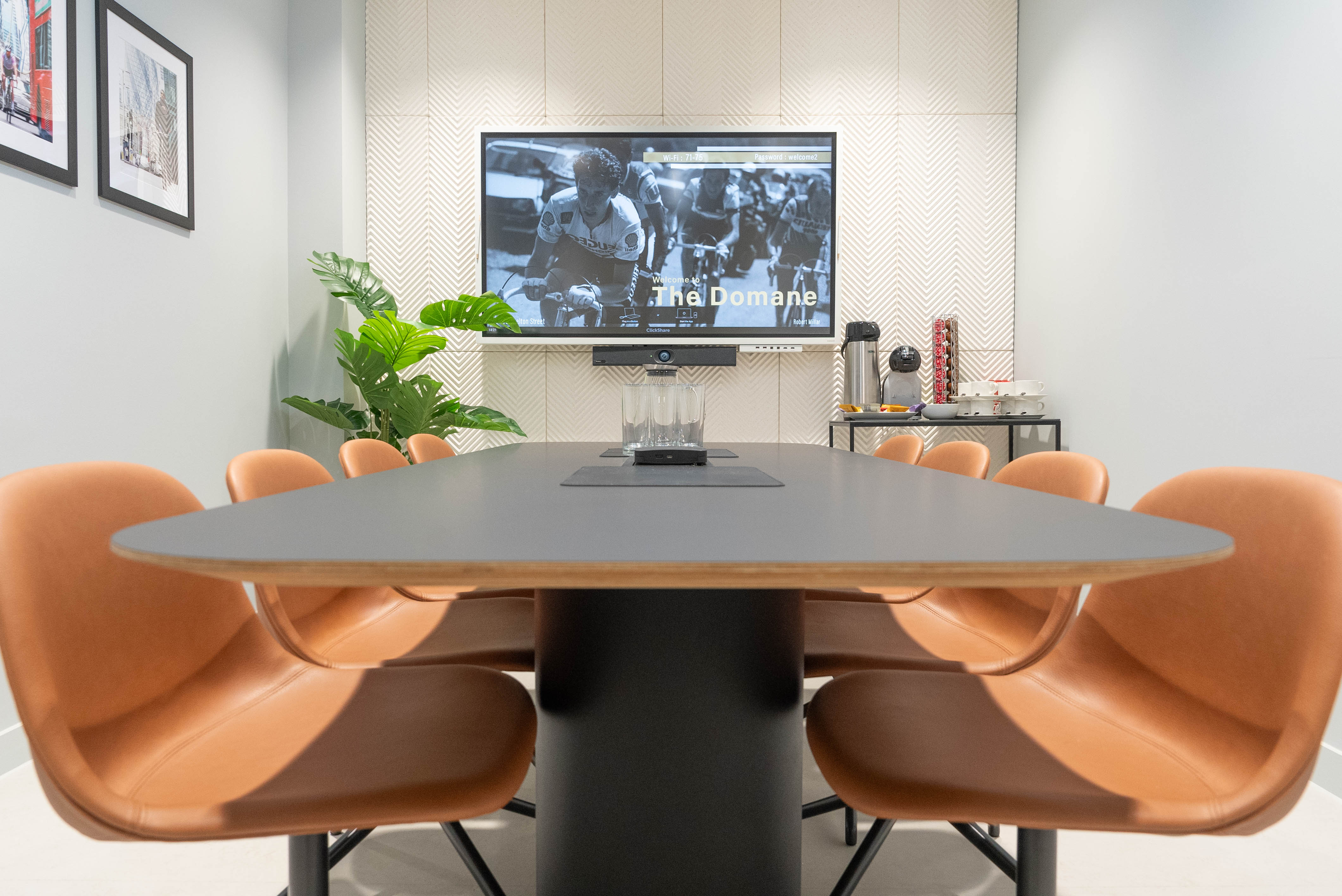 Modern conference room with oval table, leather chairs, ideal for meetings and presentations.