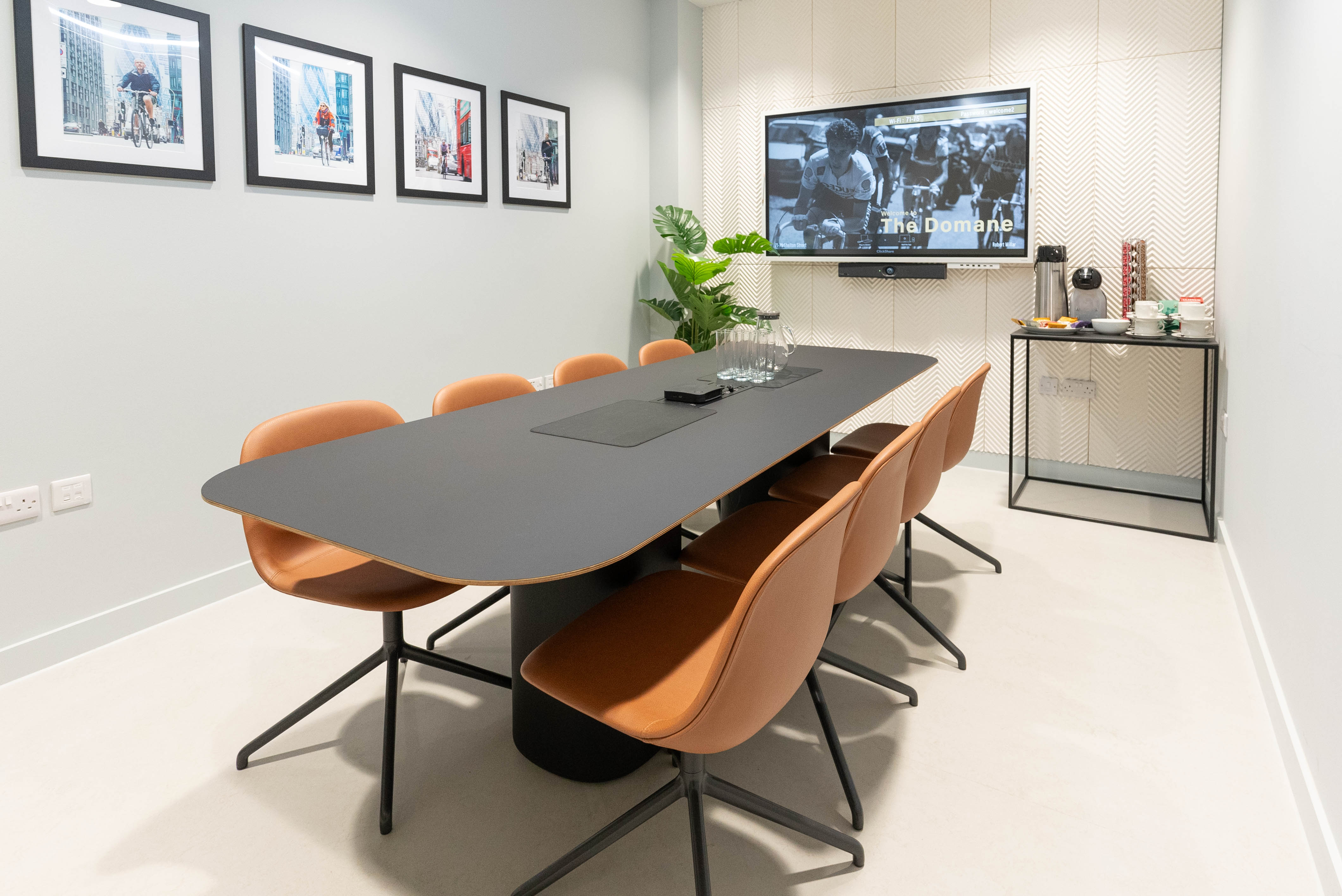 Modern meeting room with black table, orange chairs, ideal for collaboration and presentations.
