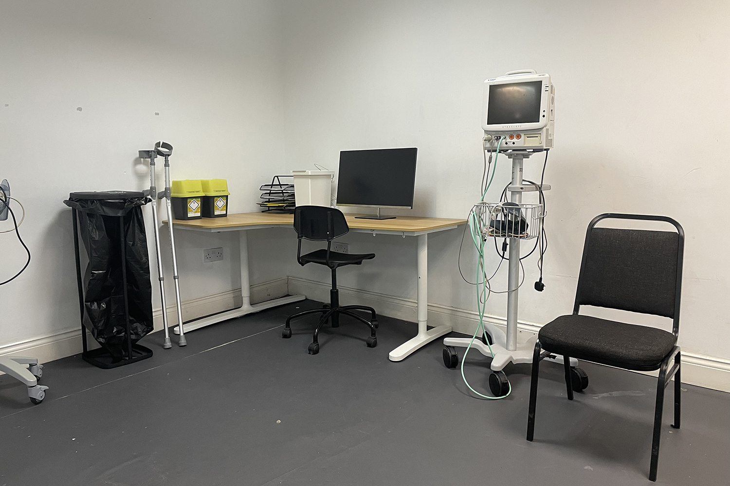 Minimalist medical consultation room with desk, computer, and equipment for events.