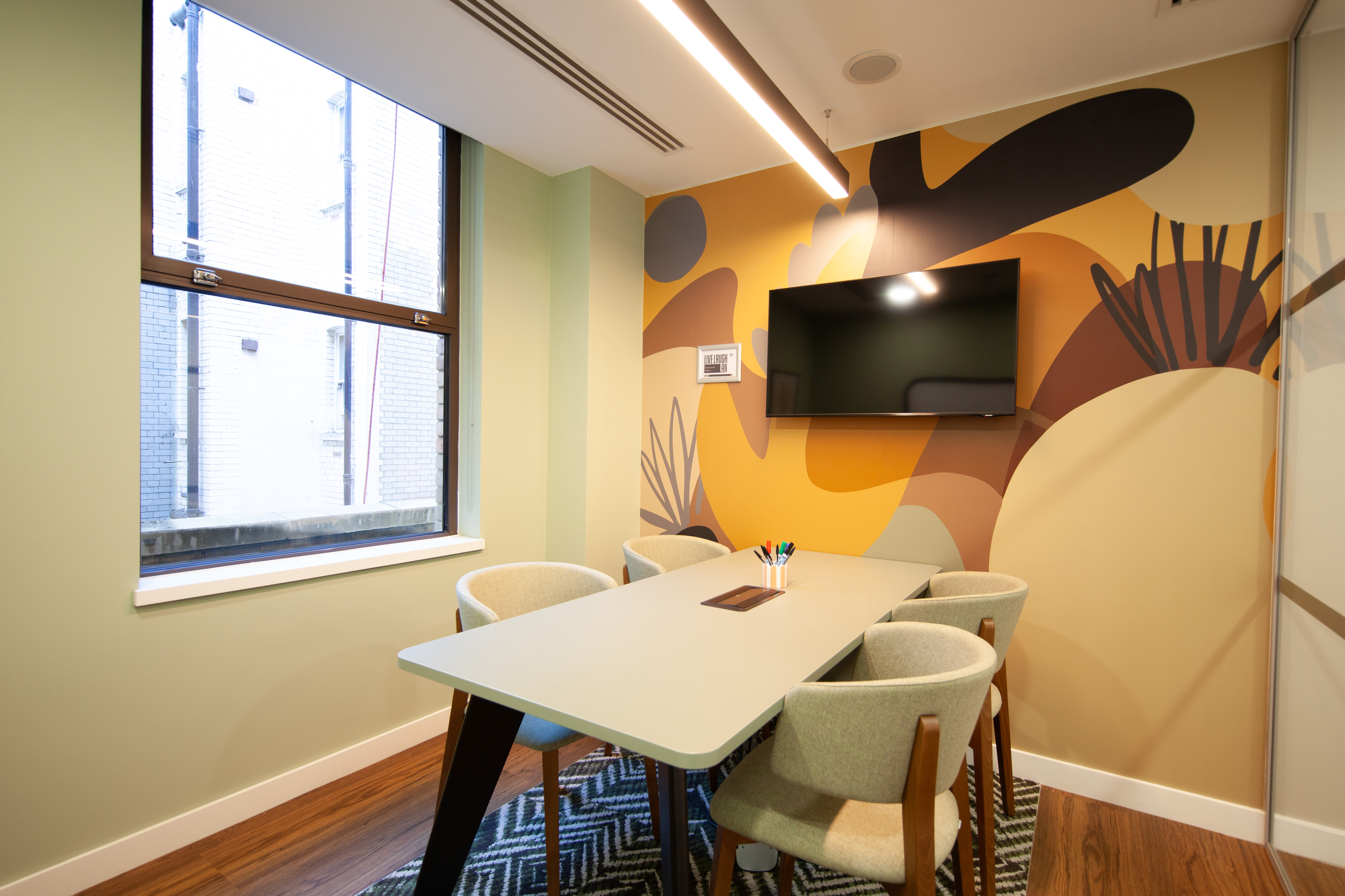Modern meeting room at Runway East Bloomsbury with stylish table and vibrant wall art.