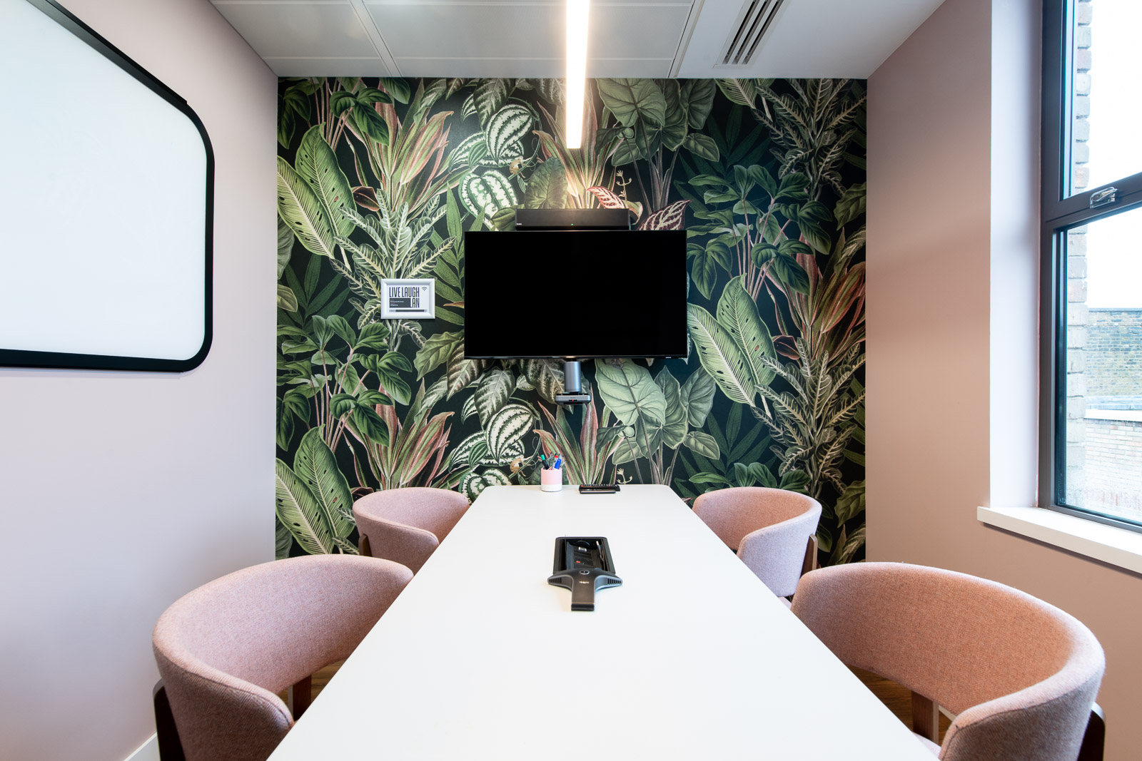 Modern meeting room with white table, pink chairs, ideal for brainstorming sessions.