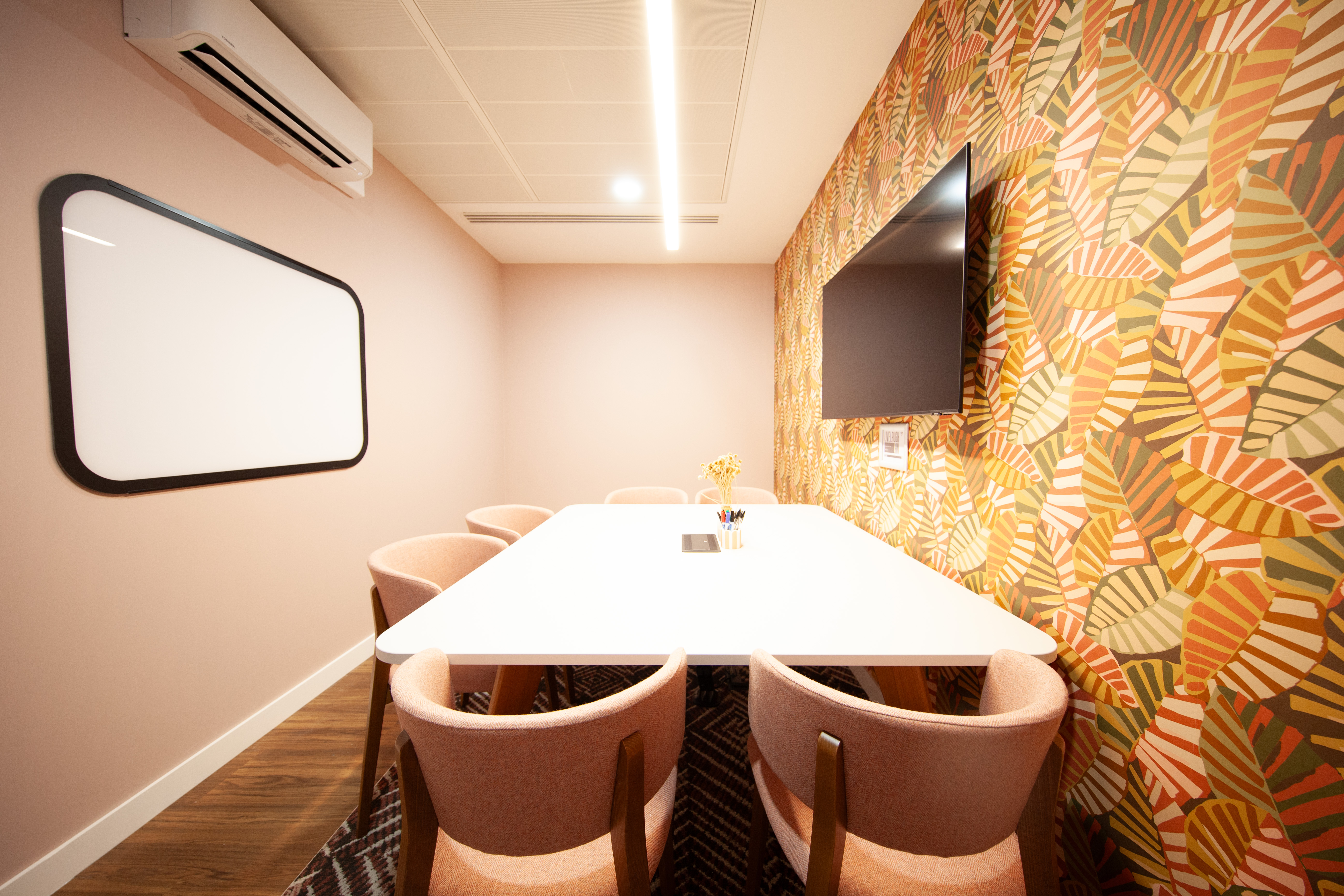 Modern meeting room in Pullman, featuring a white table and pink chairs for workshops.