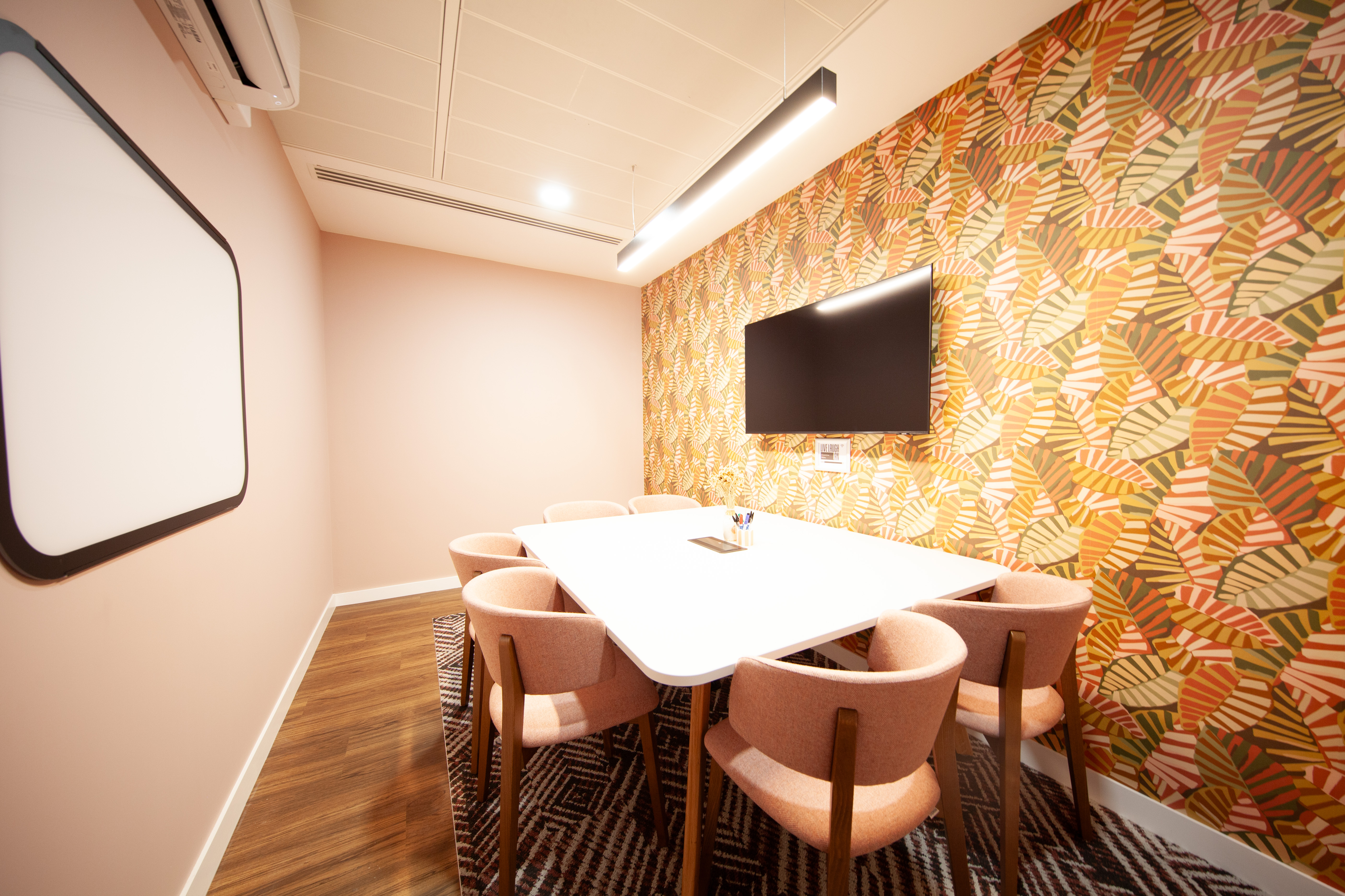 Modern meeting room in Pullman, featuring a large white table and pink chairs for workshops.