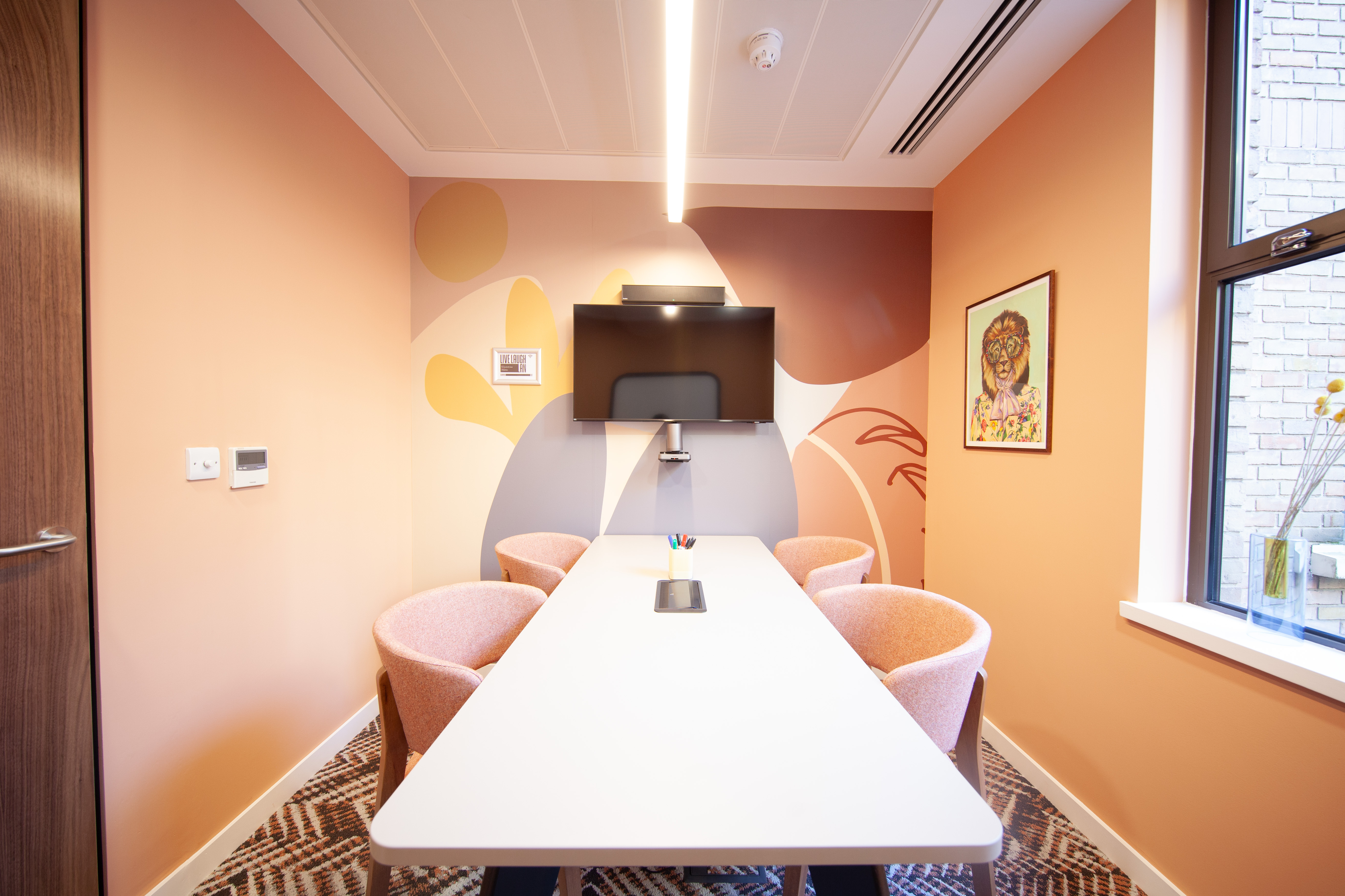 Modern meeting room with white table, pink chairs for collaborative sessions at Runway East Bloomsbury.