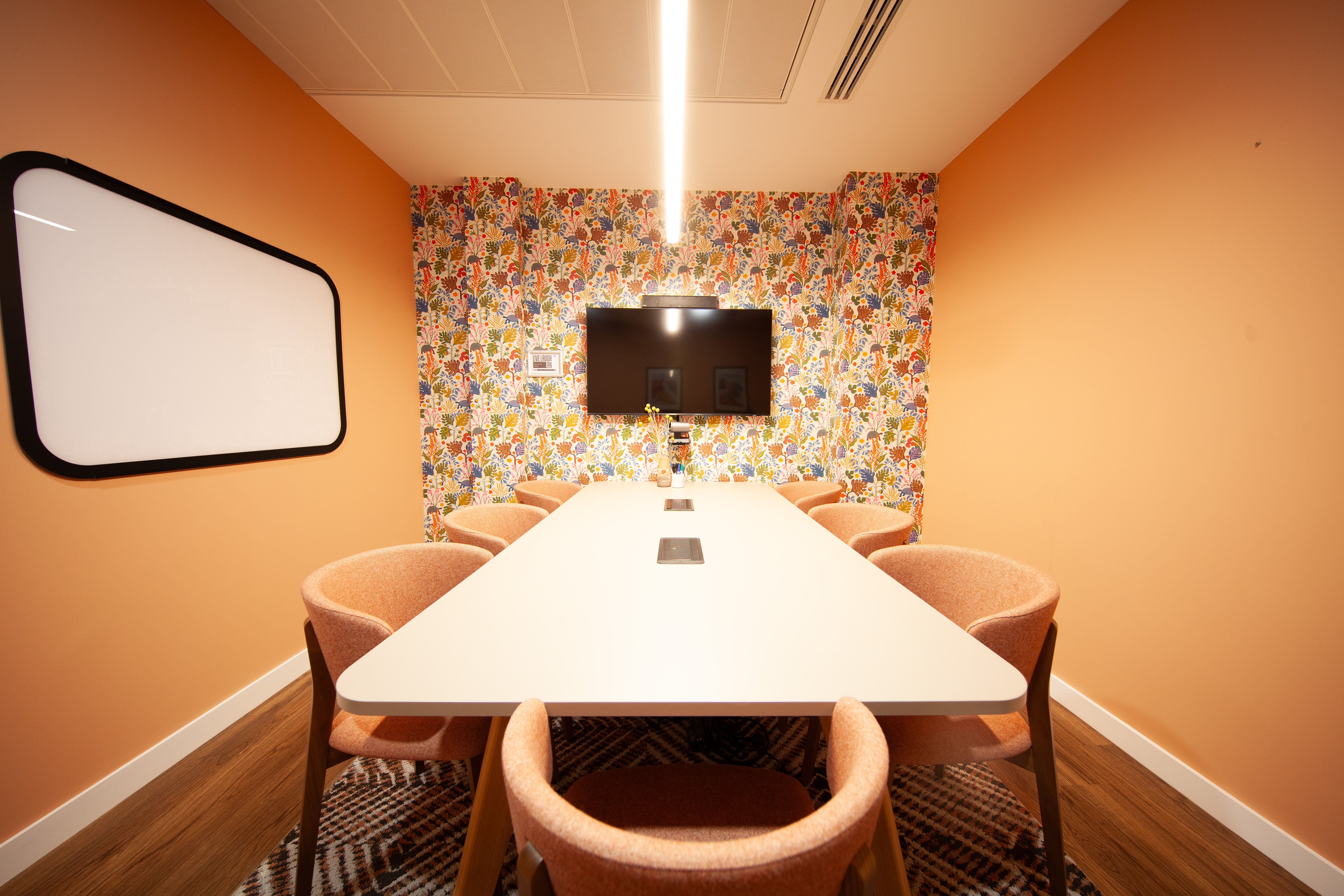 Modern meeting room with floral wallpaper, ideal for brainstorming sessions.