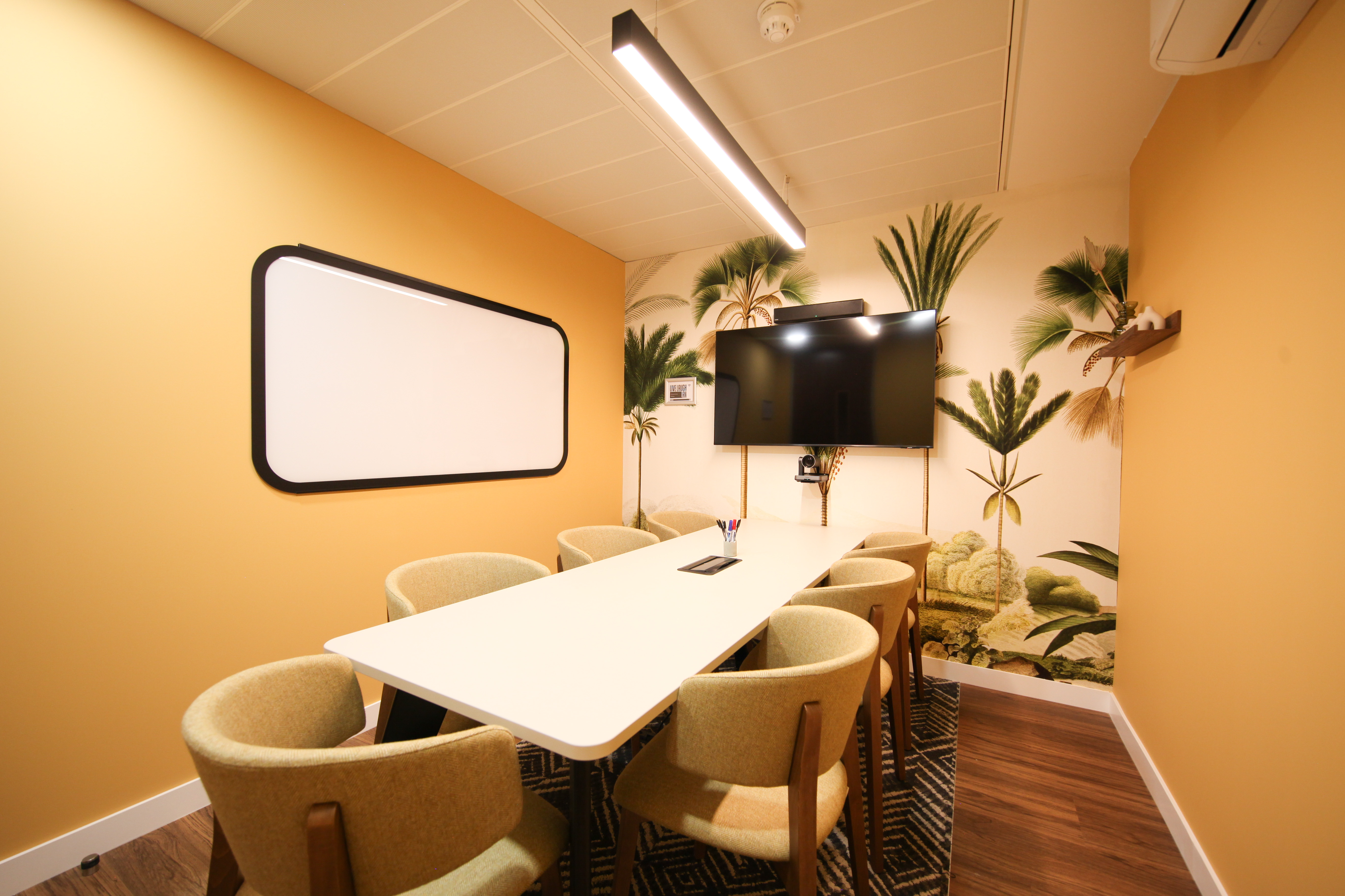Modern meeting room with white table, orange walls, ideal for collaborative events.