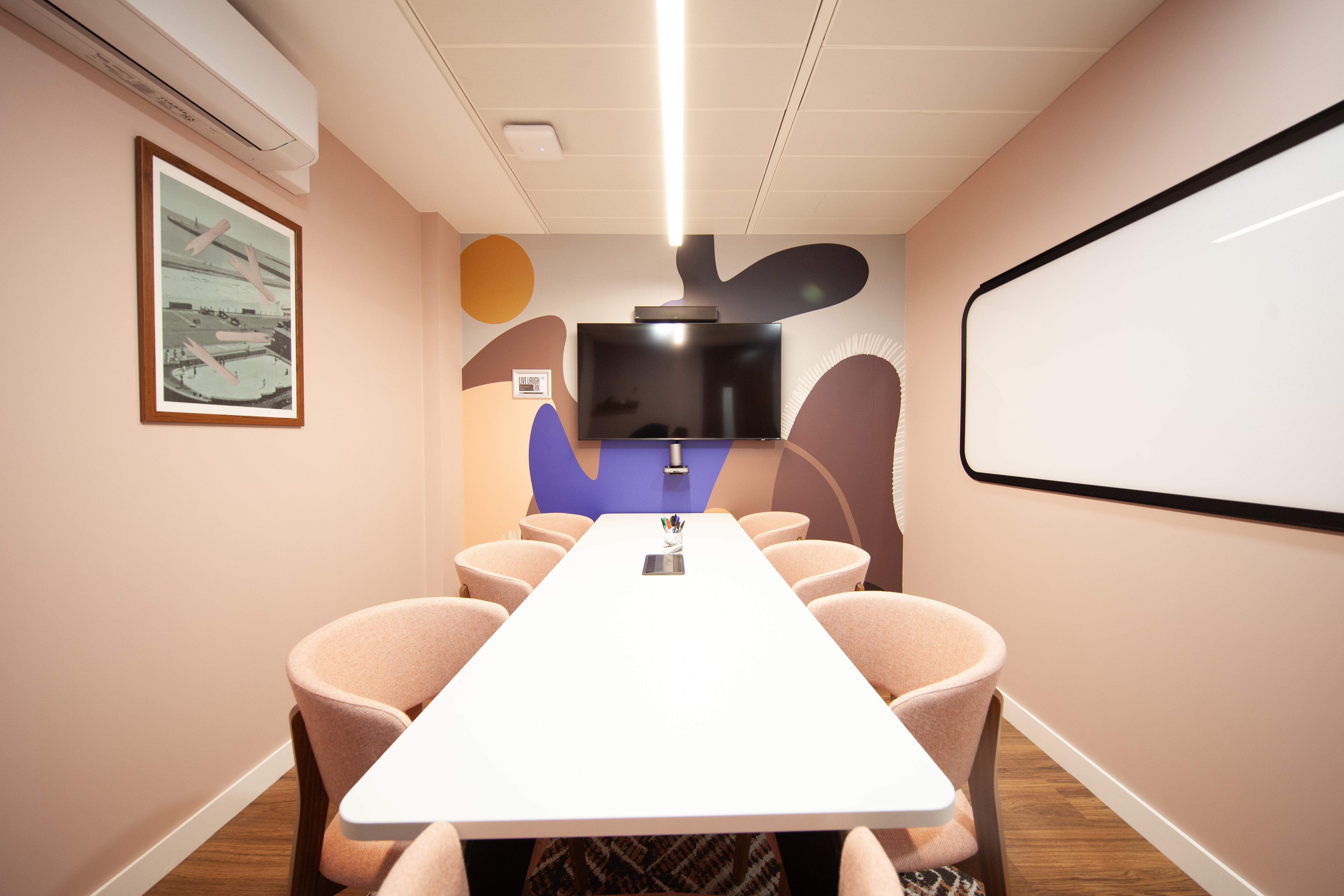 Modern meeting room with sleek white table, ideal for brainstorming sessions.