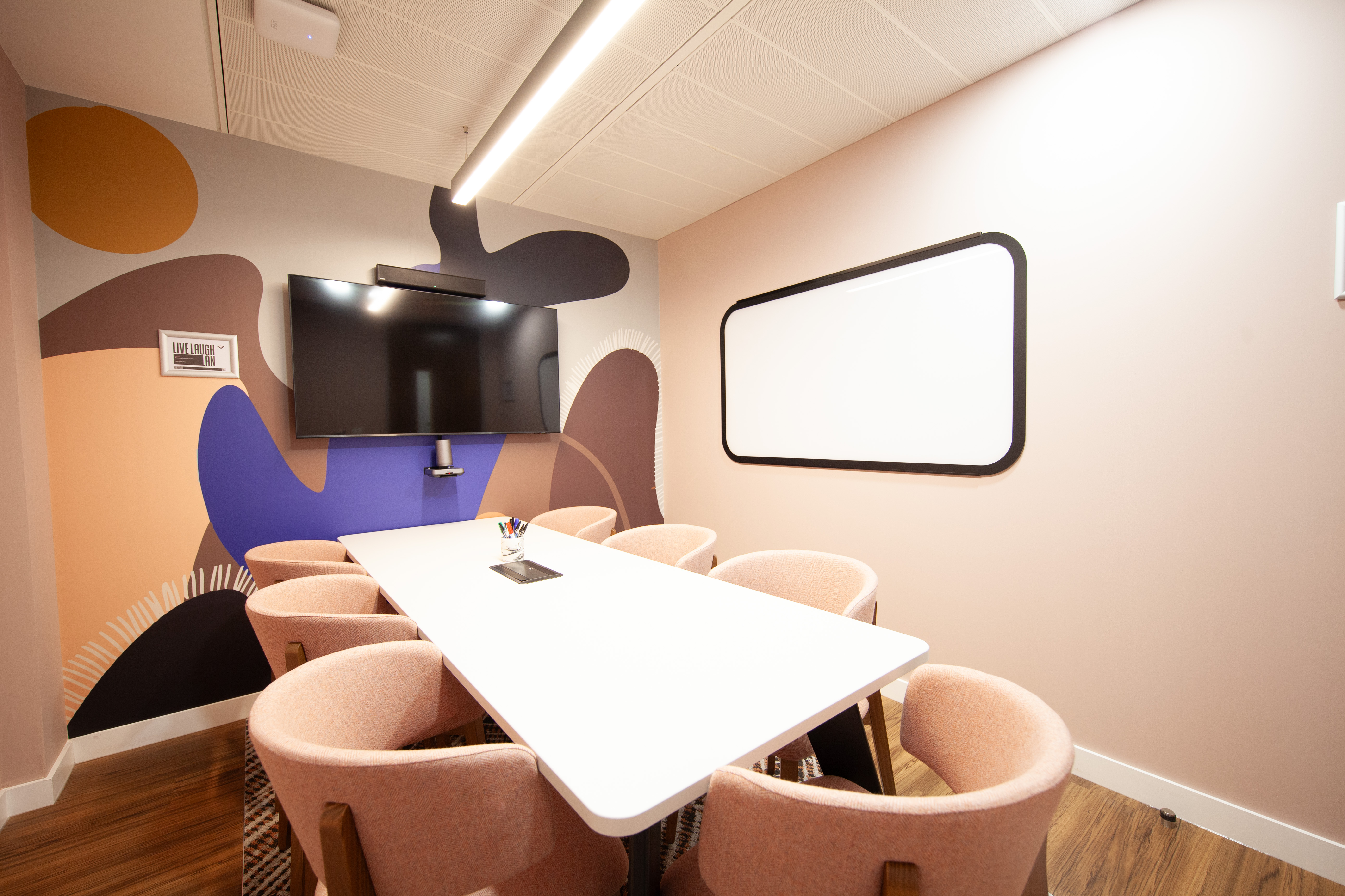 Modern meeting room with white table, pink chairs for collaborative workshops.