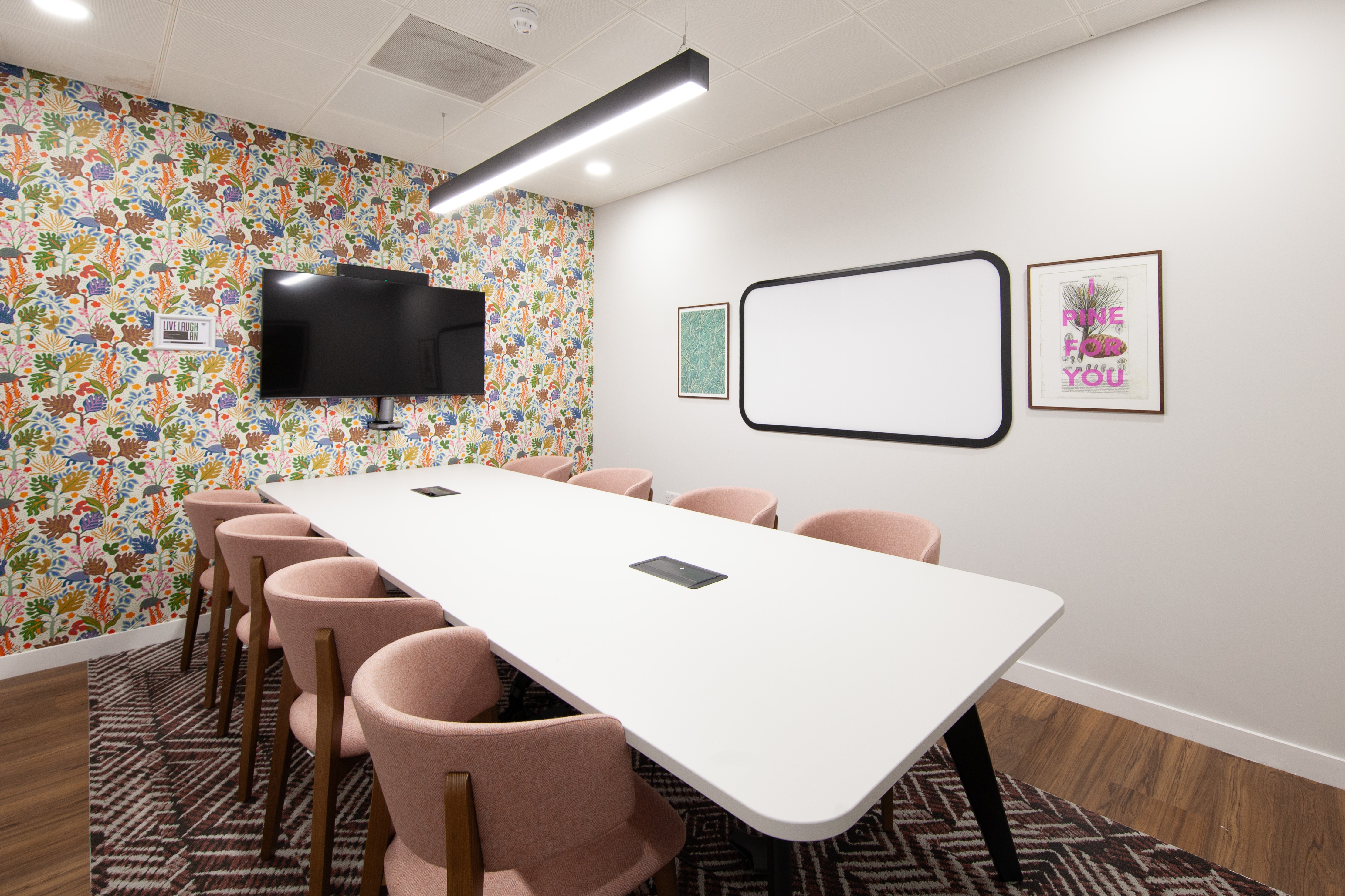 Modern meeting room with large white table and pink chairs at Runway East Bloomsbury.