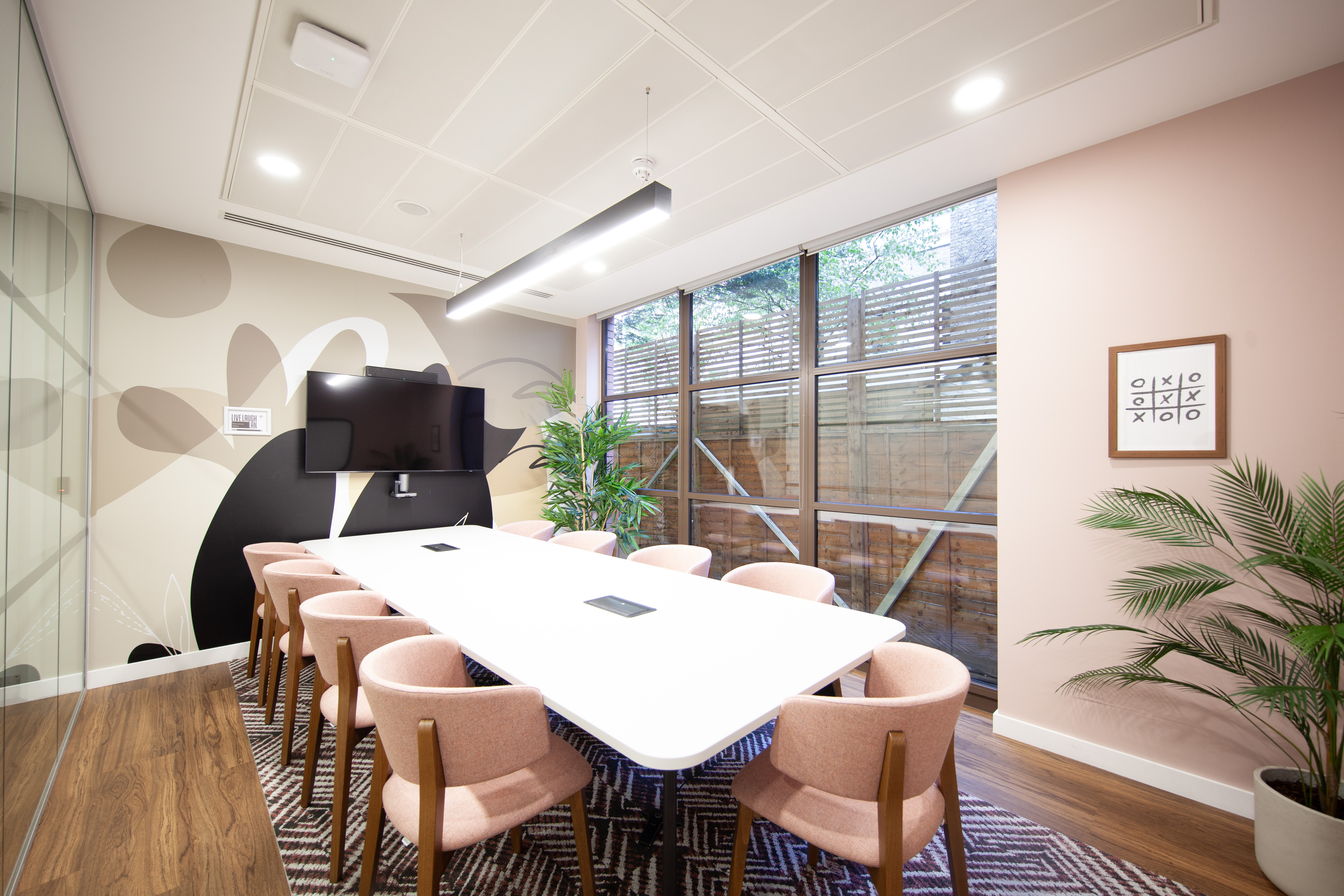 Modern meeting room with large white table and pink chairs for creative collaboration.
