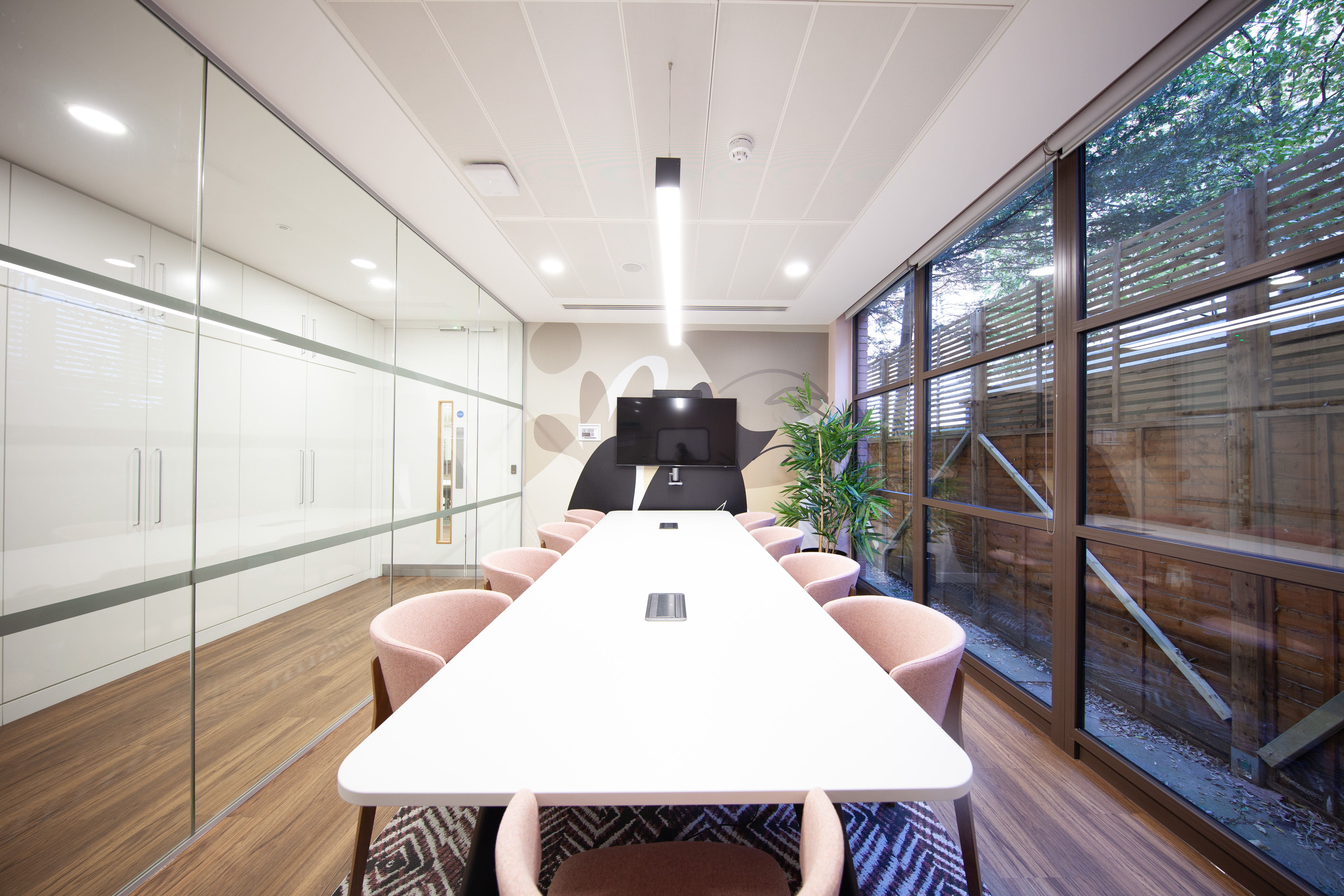 Modern meeting room with sleek table, ideal for hybrid meetings and presentations.