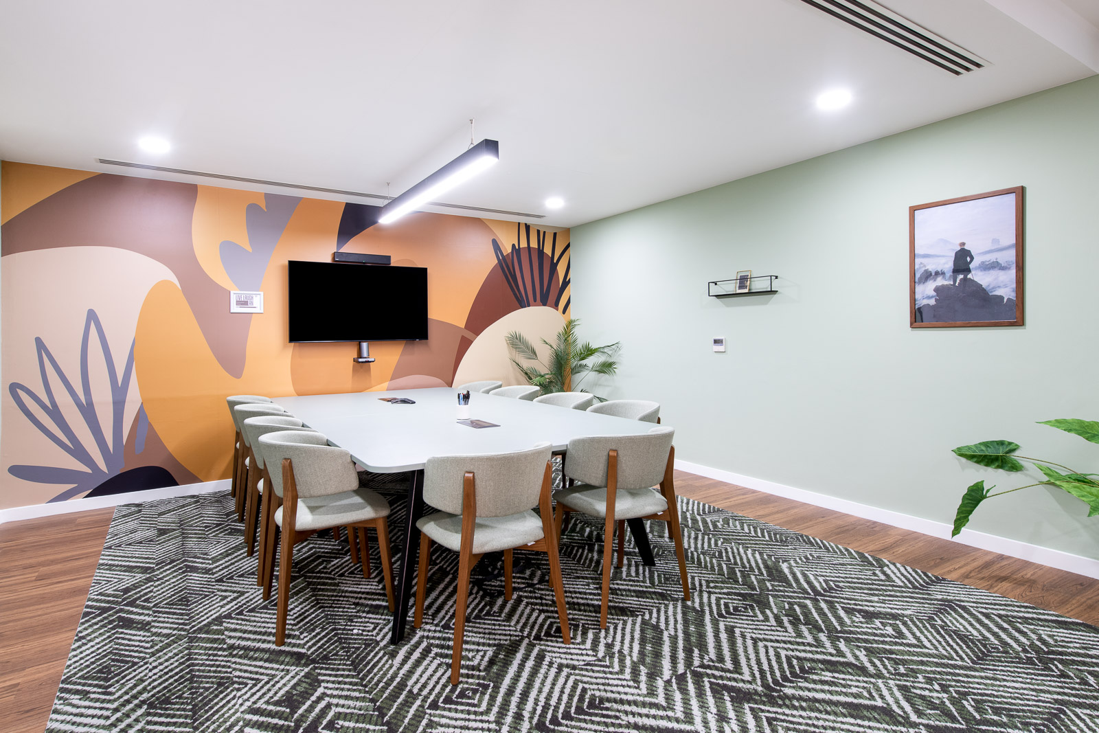 Modern meeting room with large table, vibrant art, perfect for collaboration events.