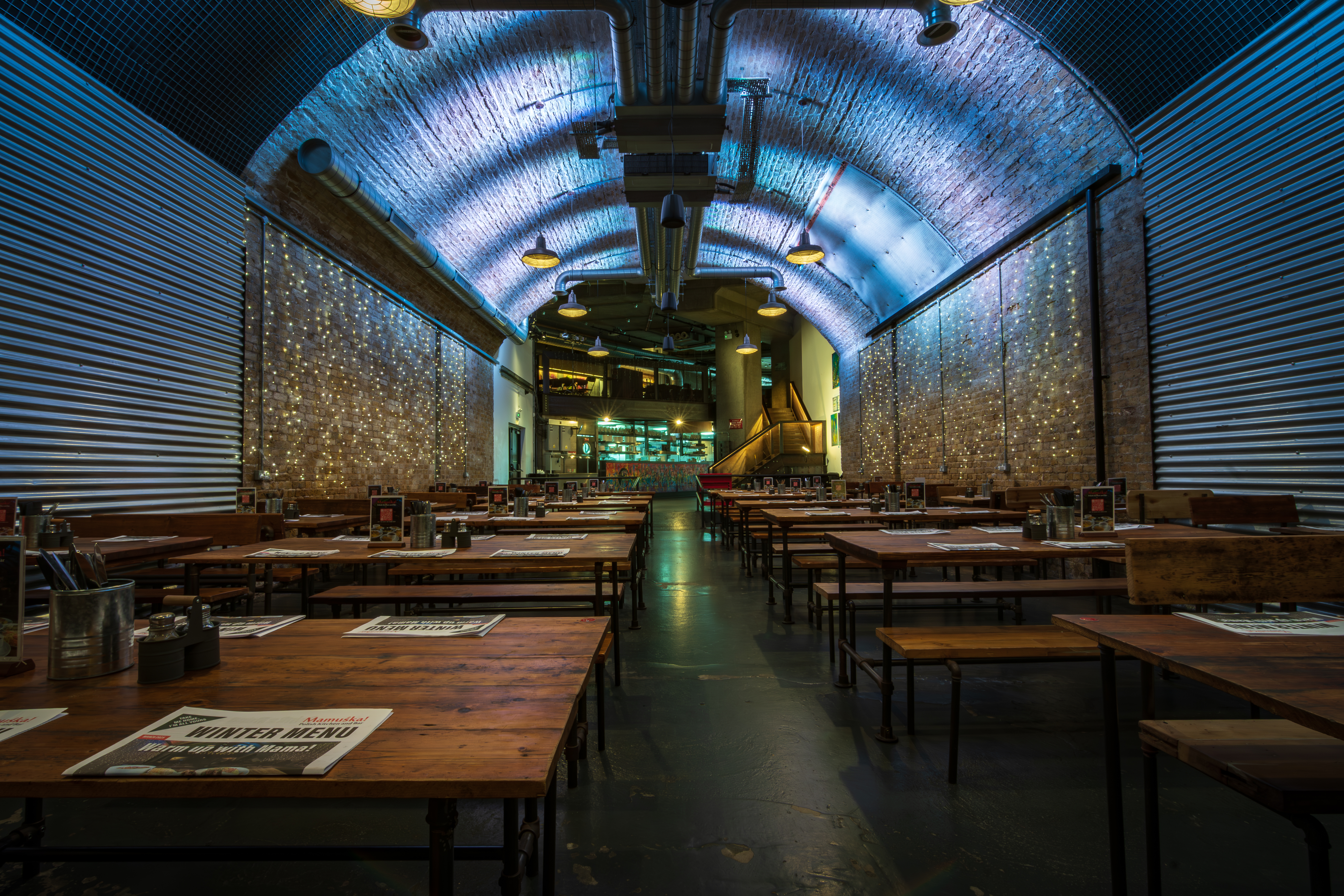 The Old Arch venue in Mamuśka, featuring warm wooden tables for event receptions.