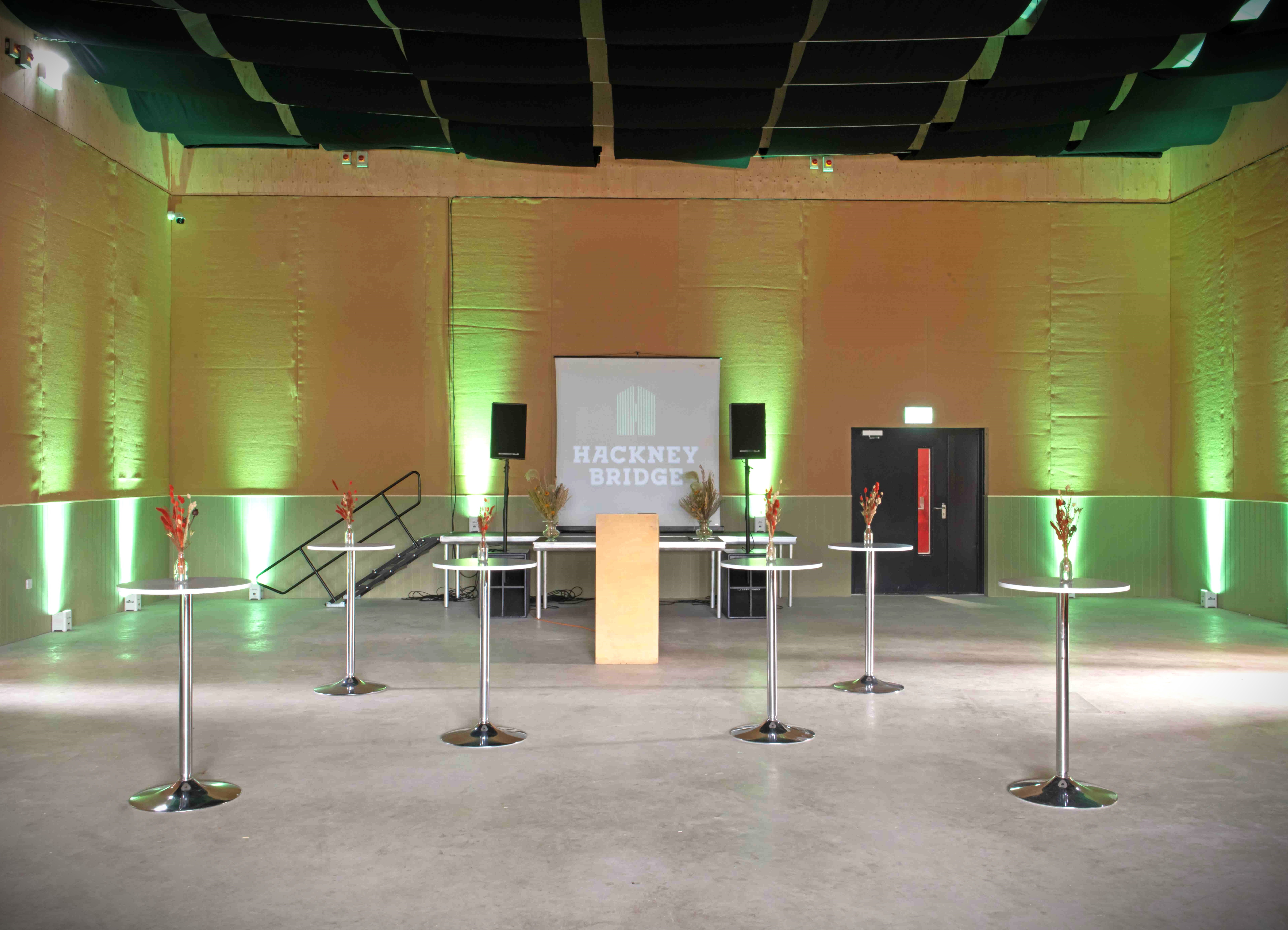 Modern event space in Hackney Bridge with green lighting for meetings and gatherings.
