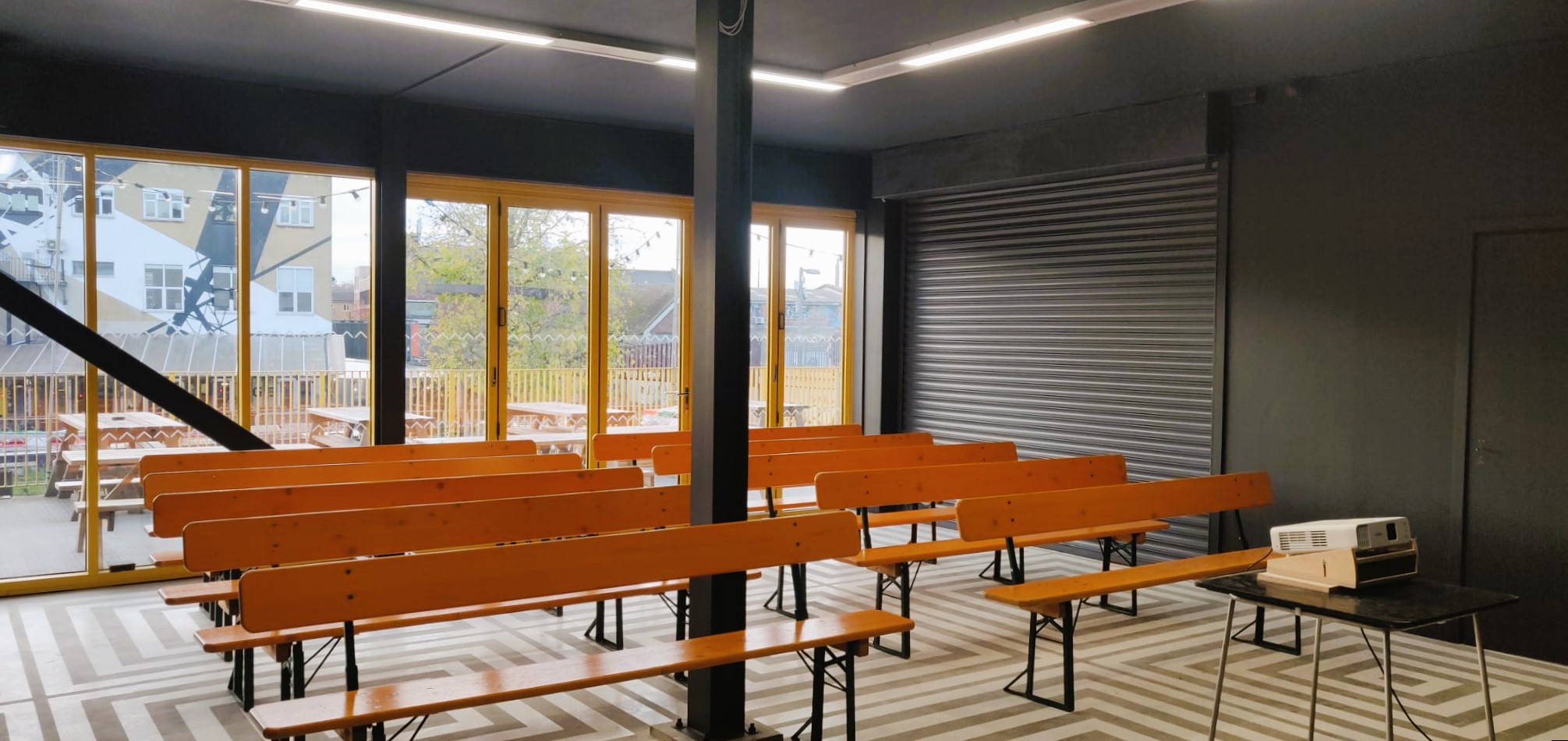 Versatile event space in Hackney Bridge with wooden benches for workshops and presentations.