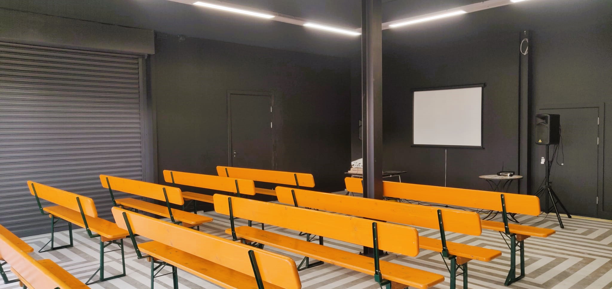 Versatile event space in Hackney Bridge with wooden benches for presentations and workshops.