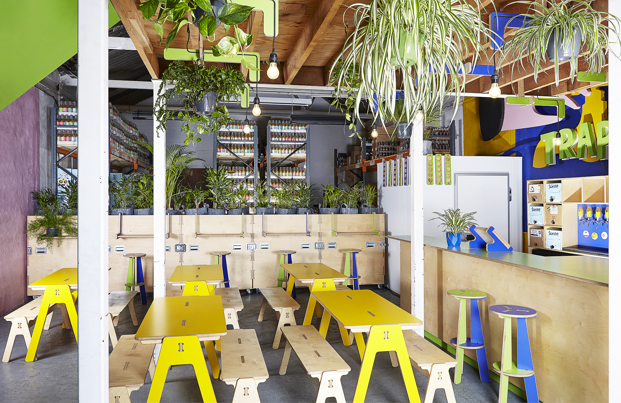Vibrant taproom with colorful furniture and greenery, perfect for casual meetings and workshops.