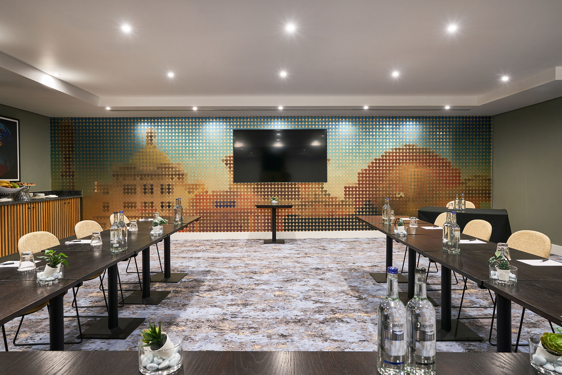 Modern meeting room at The Cumberland Hotel with dark wood tables and artistic mural.