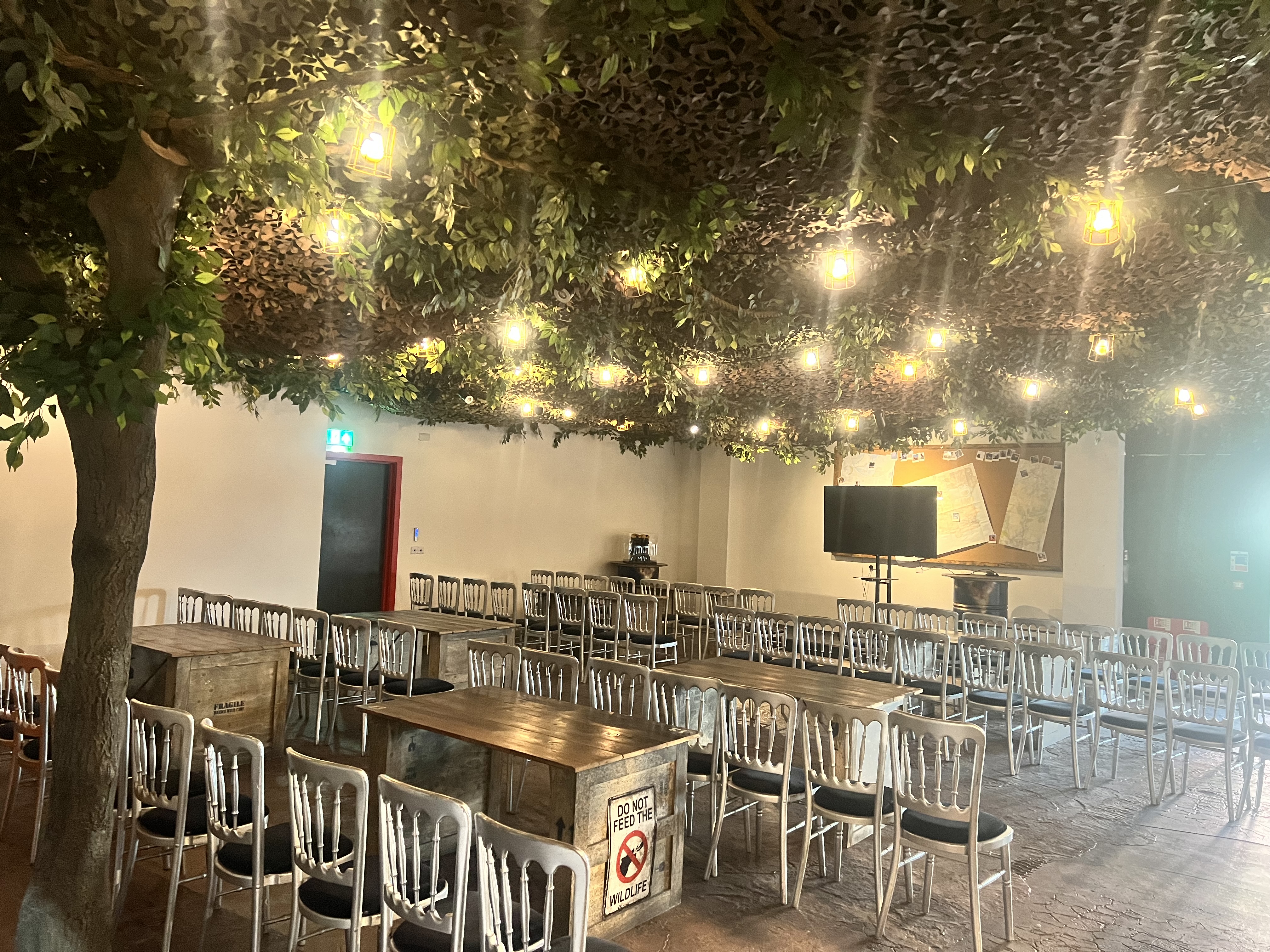 The Den at Bear Grylls Adventure: rustic event space with greenery, ideal for meetings and workshops.