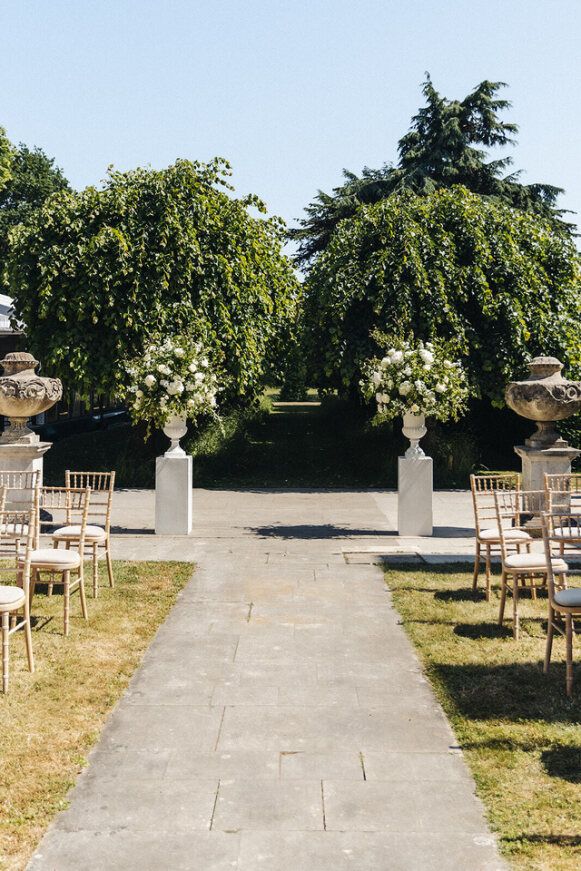 Elegant outdoor wedding ceremony at The Courtyards, Chiswick House with floral arrangements.