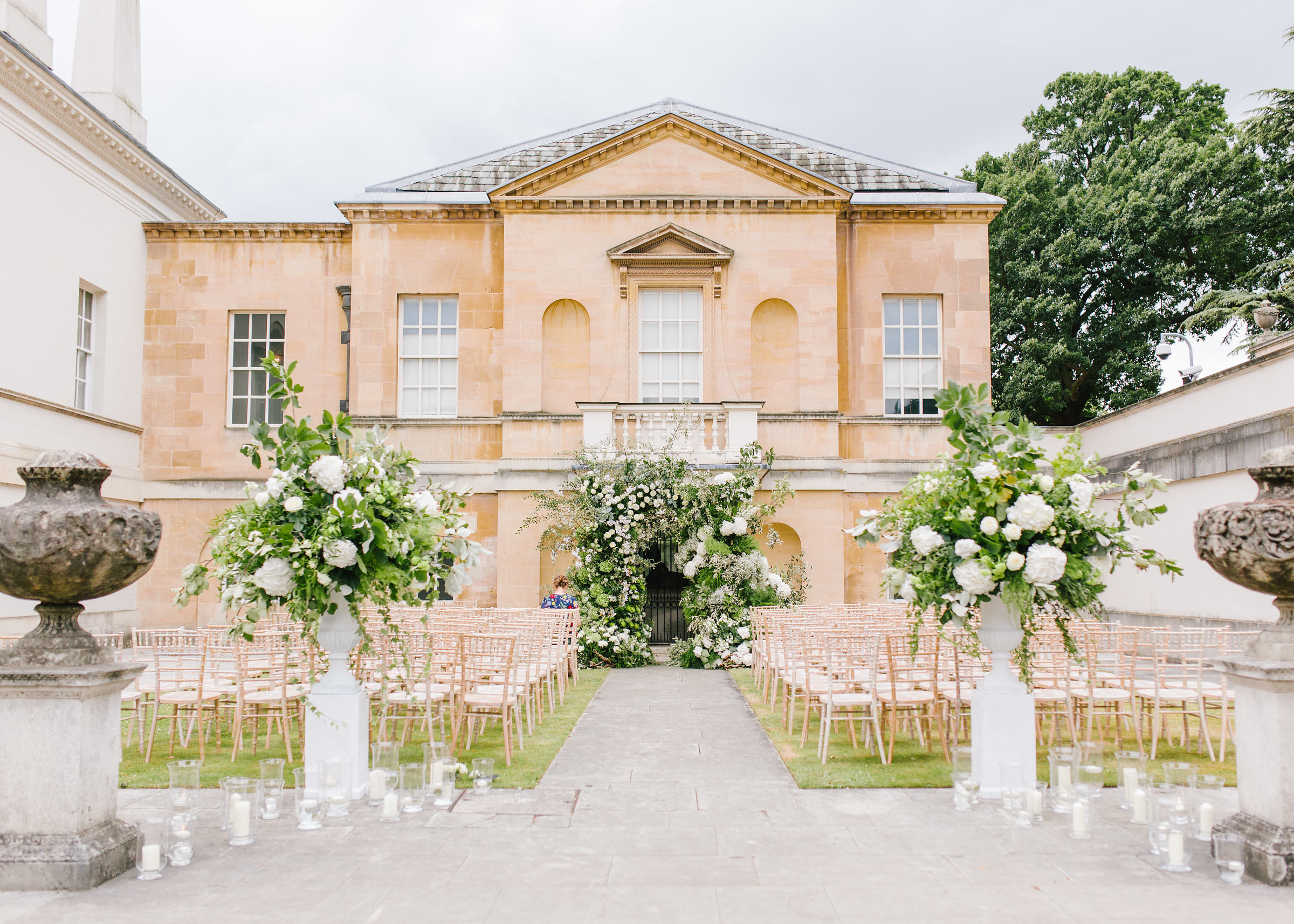 Outdoor wedding ceremony at Chiswick House with elegant floral arrangements and chiavari chairs.