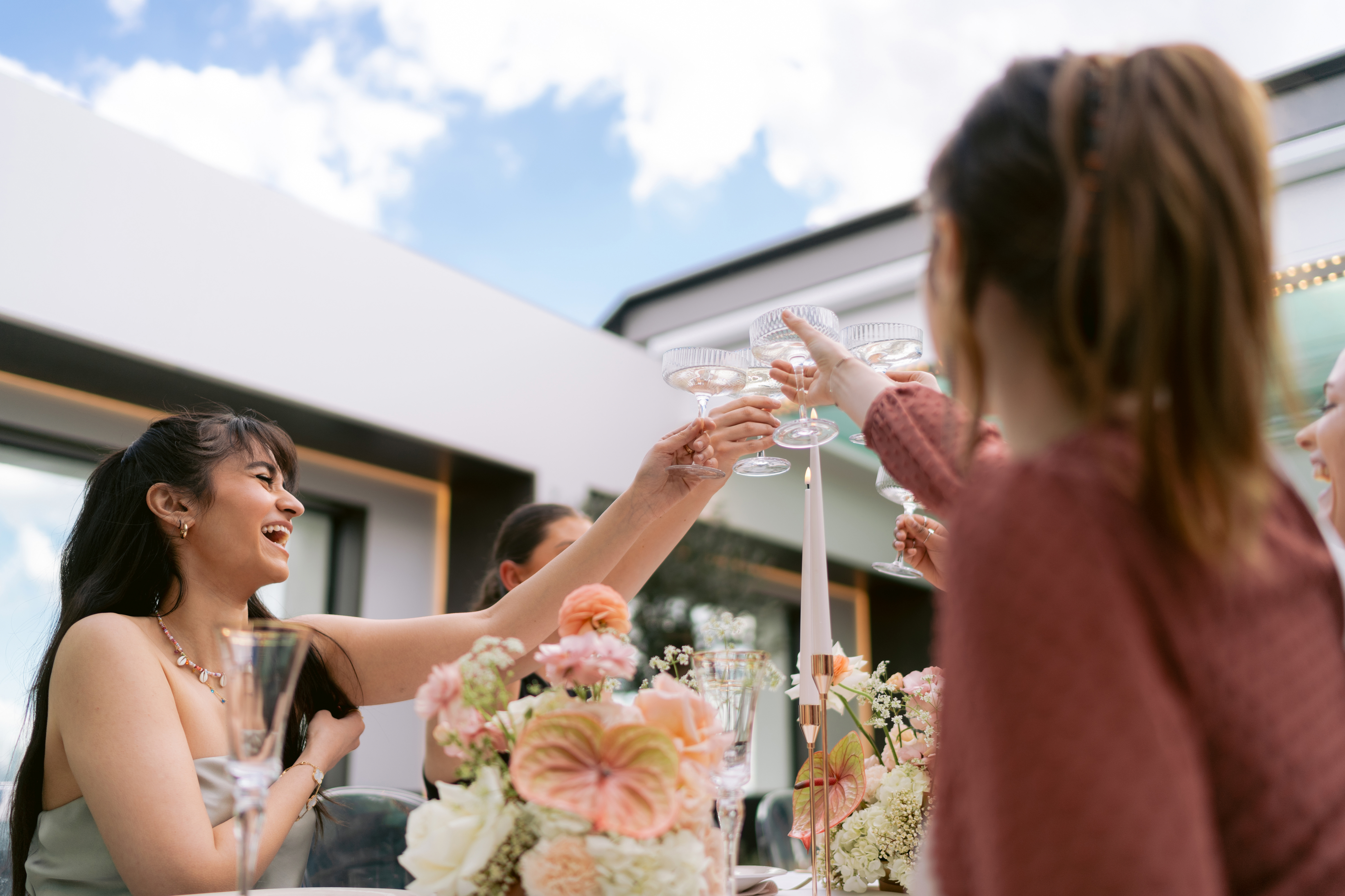 Vibrant social event at Met Lounge with elegant floral arrangements and toasting guests.