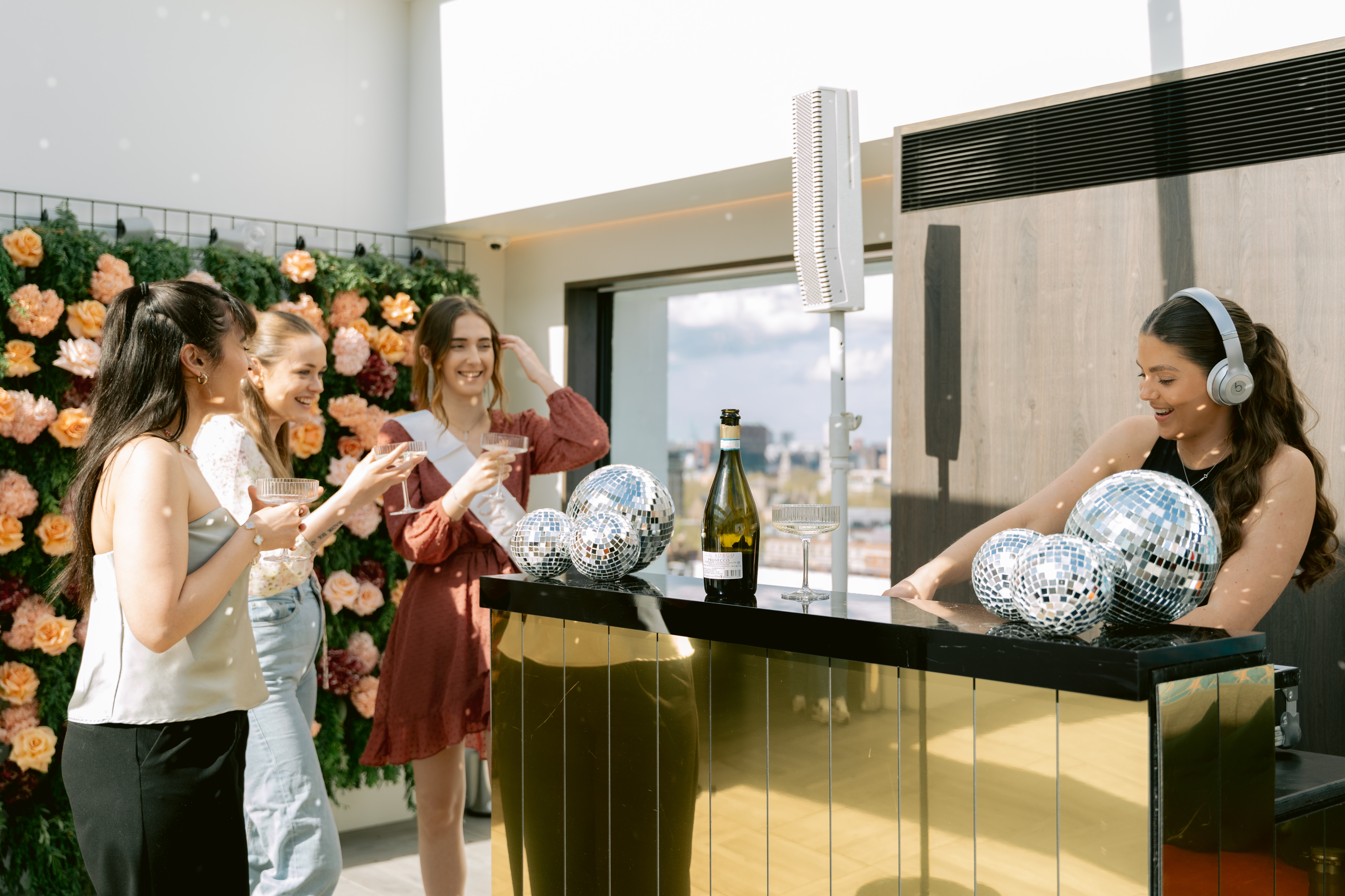 Vibrant event setup at Met Lounge with stylish bar, DJ, and floral backdrop.
