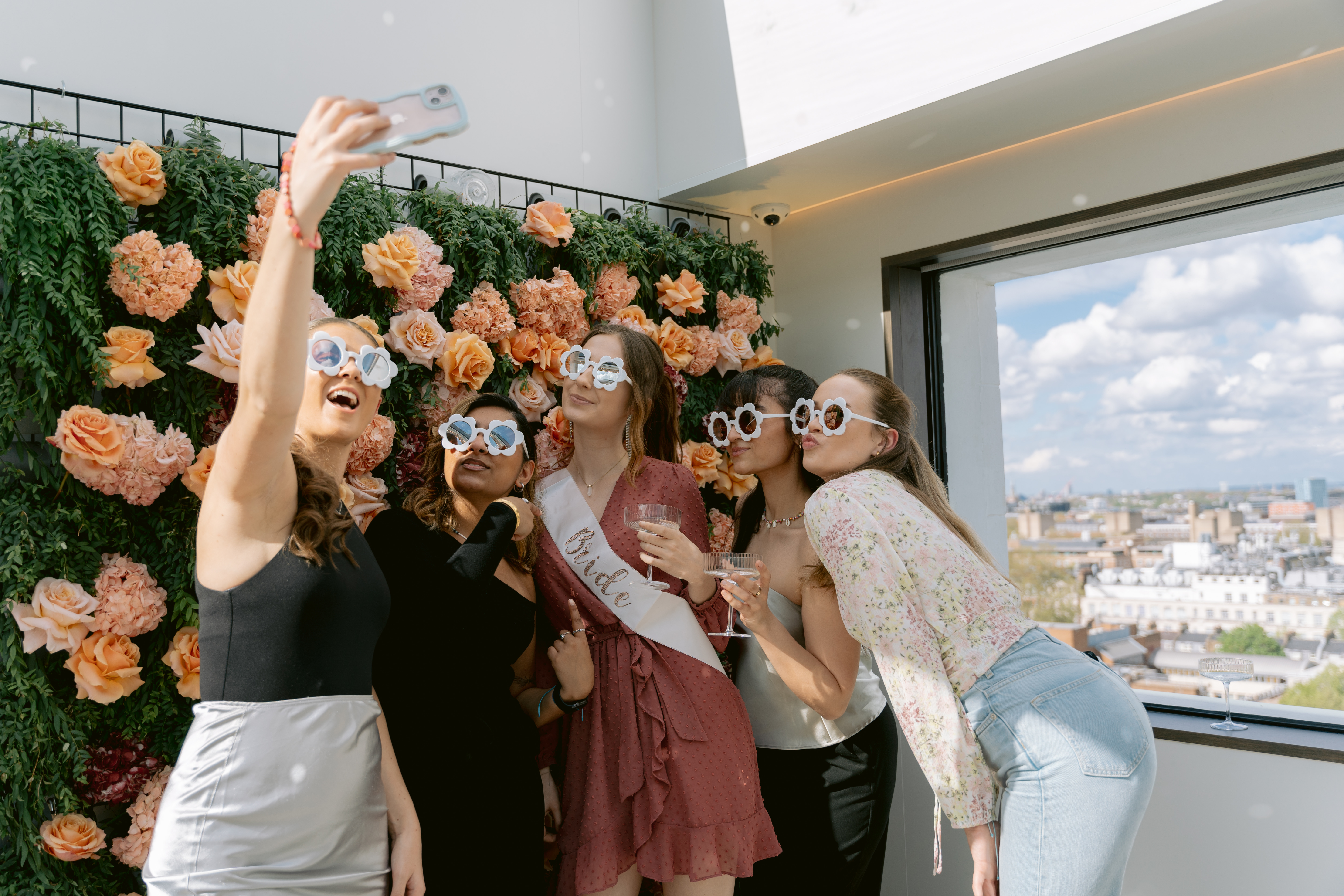 Vibrant group at Met Lounge with floral backdrop, perfect for bridal shower or birthday party.