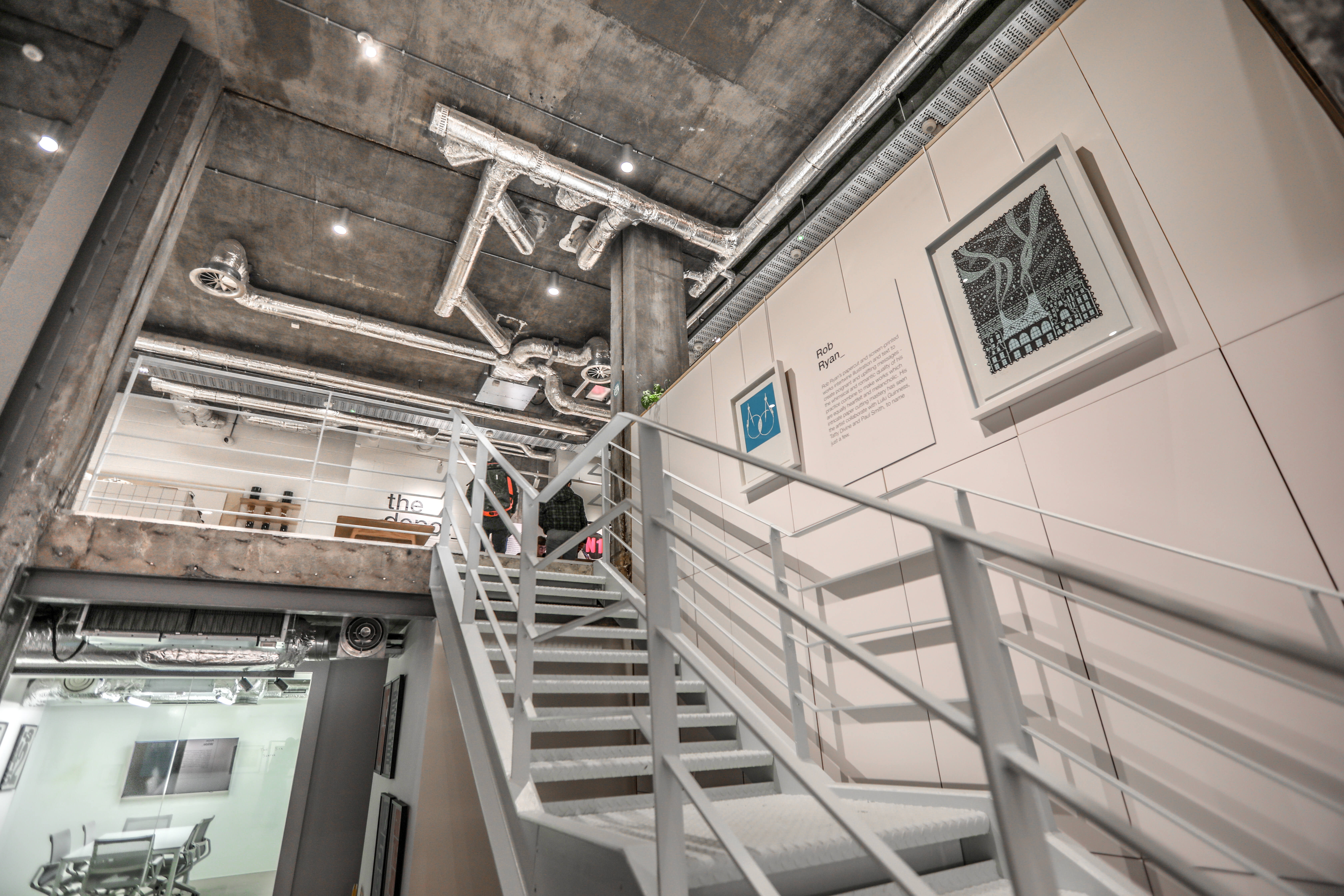 Modern industrial event space with exposed pipes, ideal for creative meetings and networking.