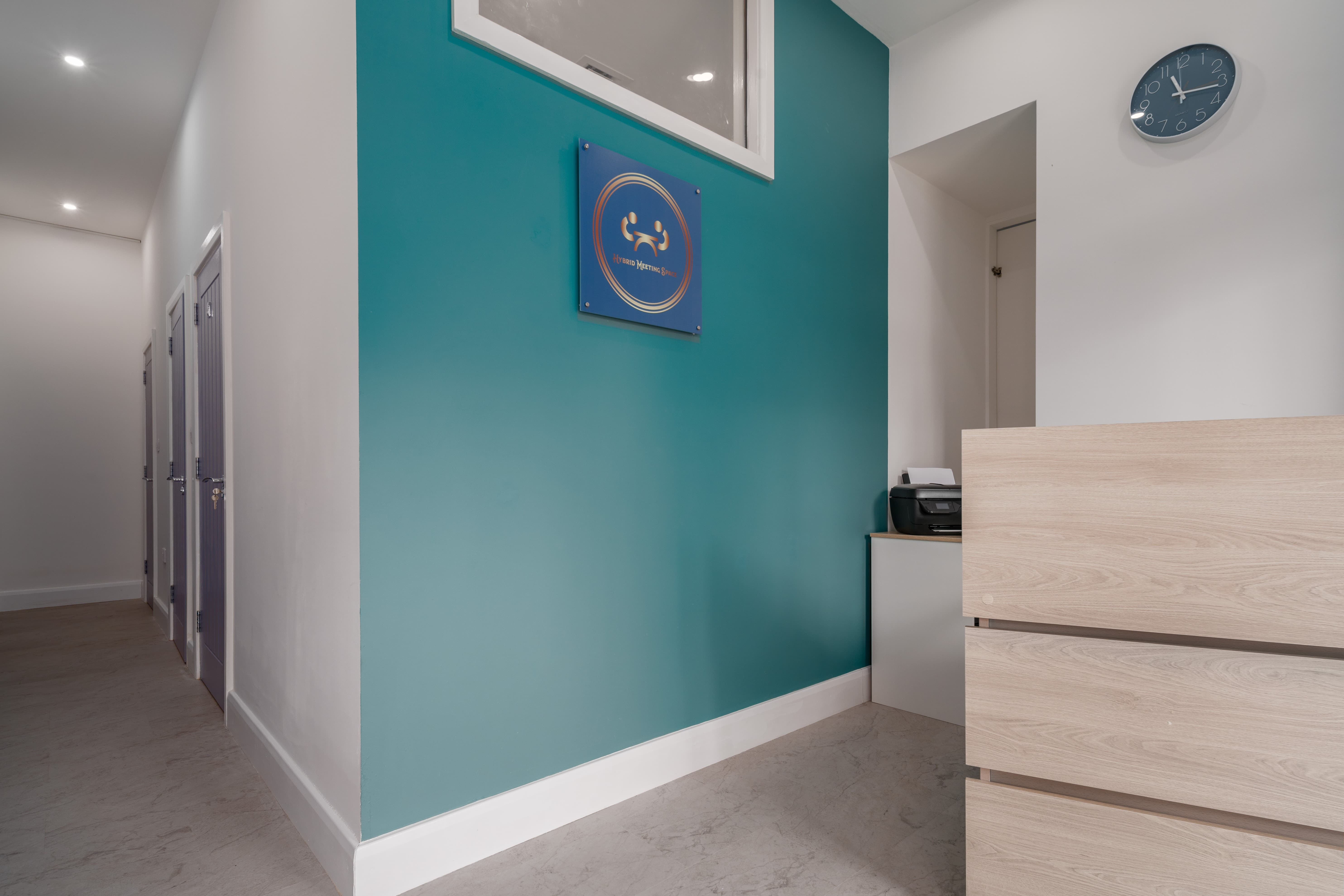 Modern hybrid meeting space with teal wall, ideal for professional events and meetings.