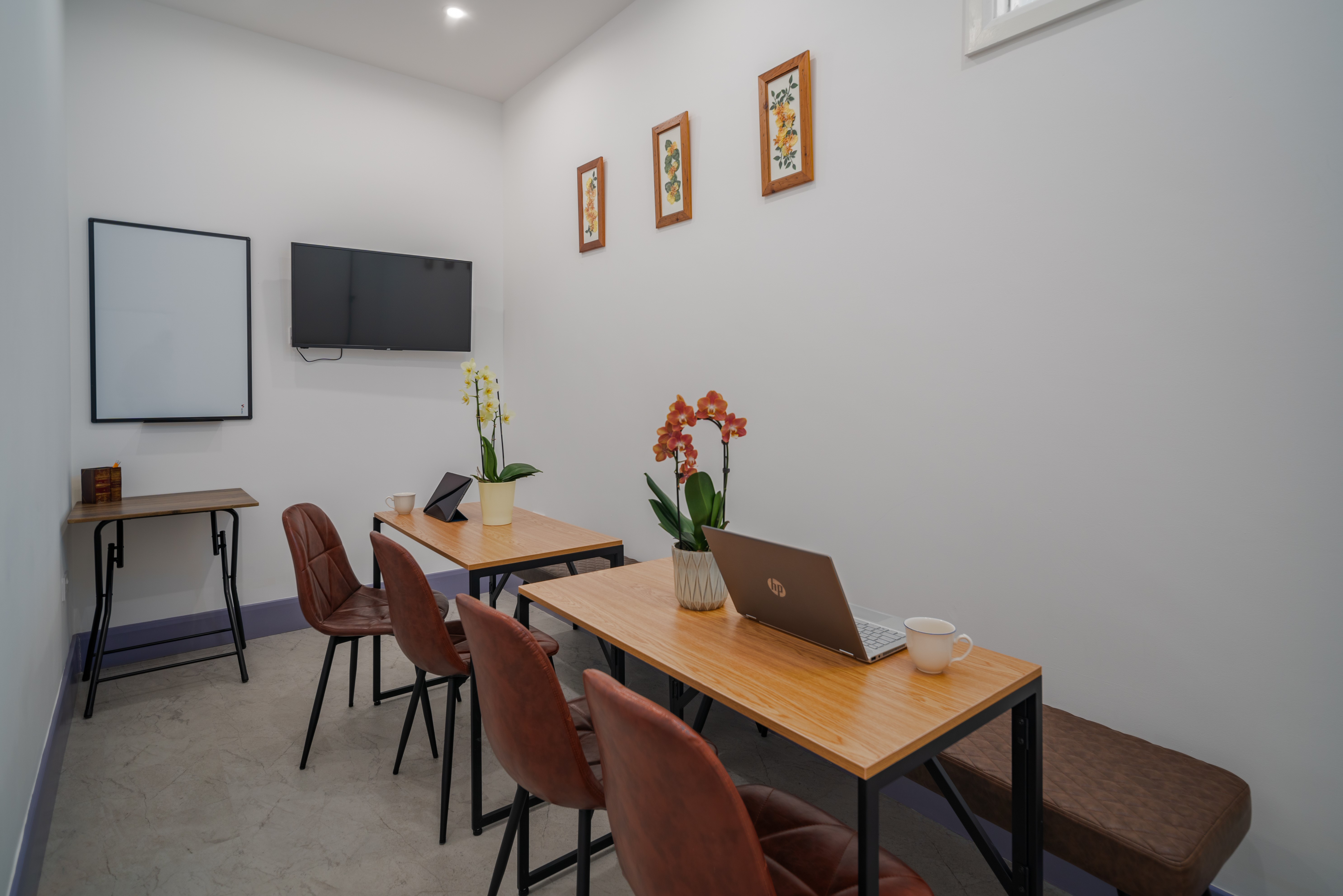 Modern hybrid meeting room with wooden tables, ideal for workshops and brainstorming sessions.