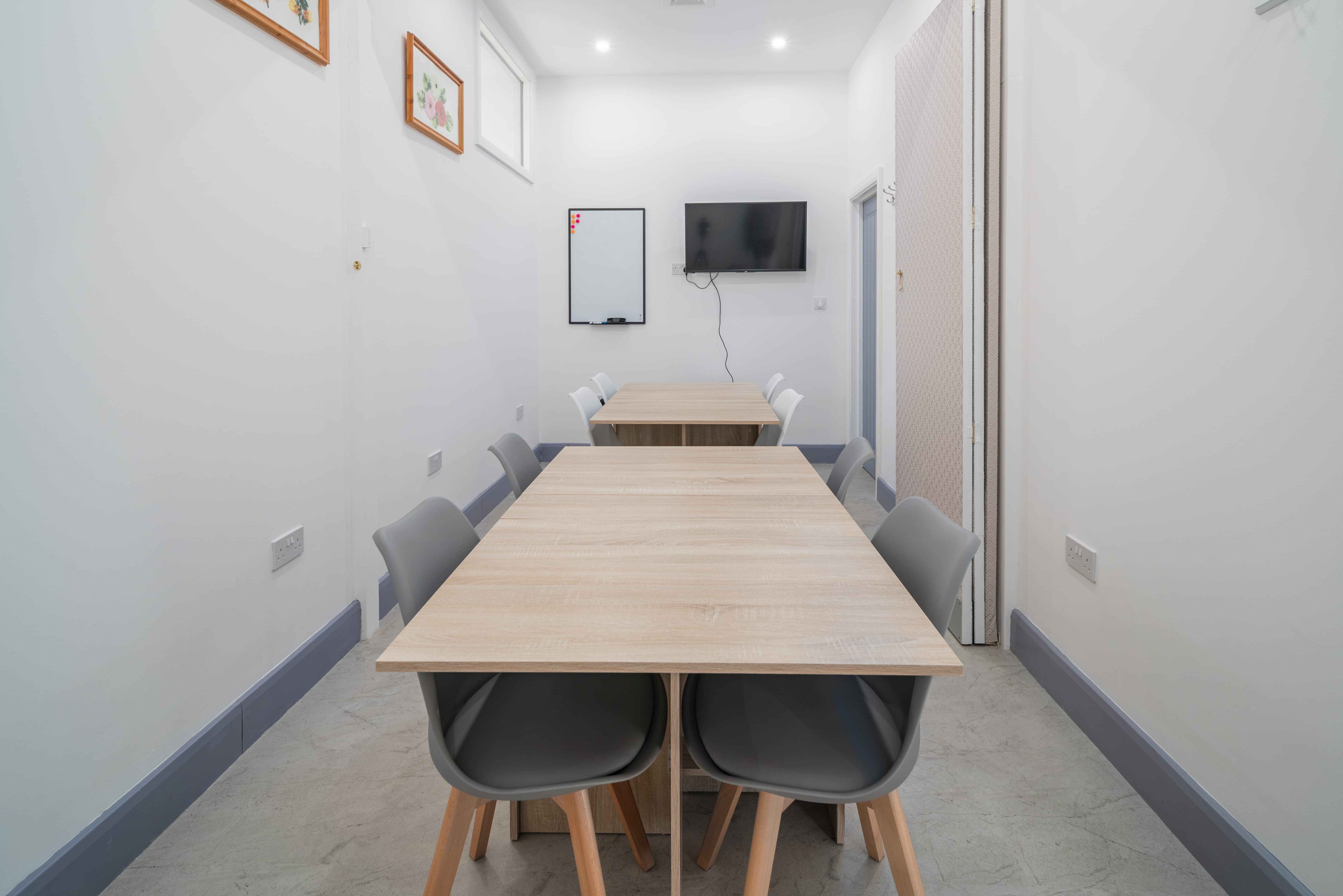 Minimalist hybrid meeting room with wooden tables, ideal for workshops and presentations.